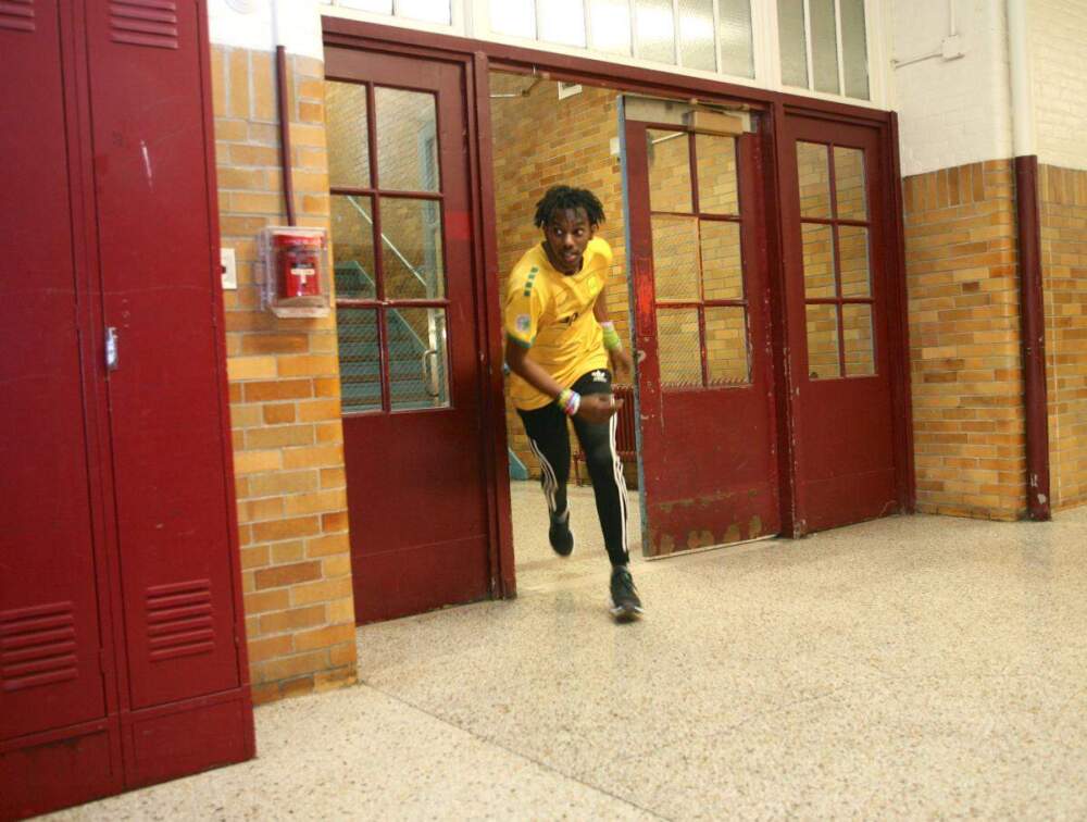 Yevegueny Glemaud bursts through a doorway en route to the finish line by the principal’s office. (Seth Daniel/ Dorchester Reporter)