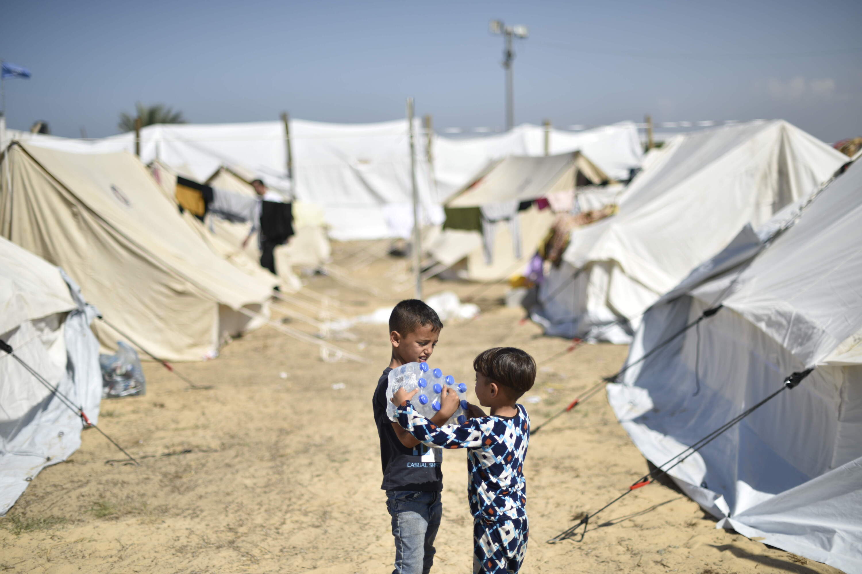 Yamen, 7- year-old, and his brother Yazan, 4 -year-old, carrying UNICEF-supported bottled water inside the UNRWA refugee camp in Khan Yunis, southern the Gaza Strip. (Abed Zaqout)