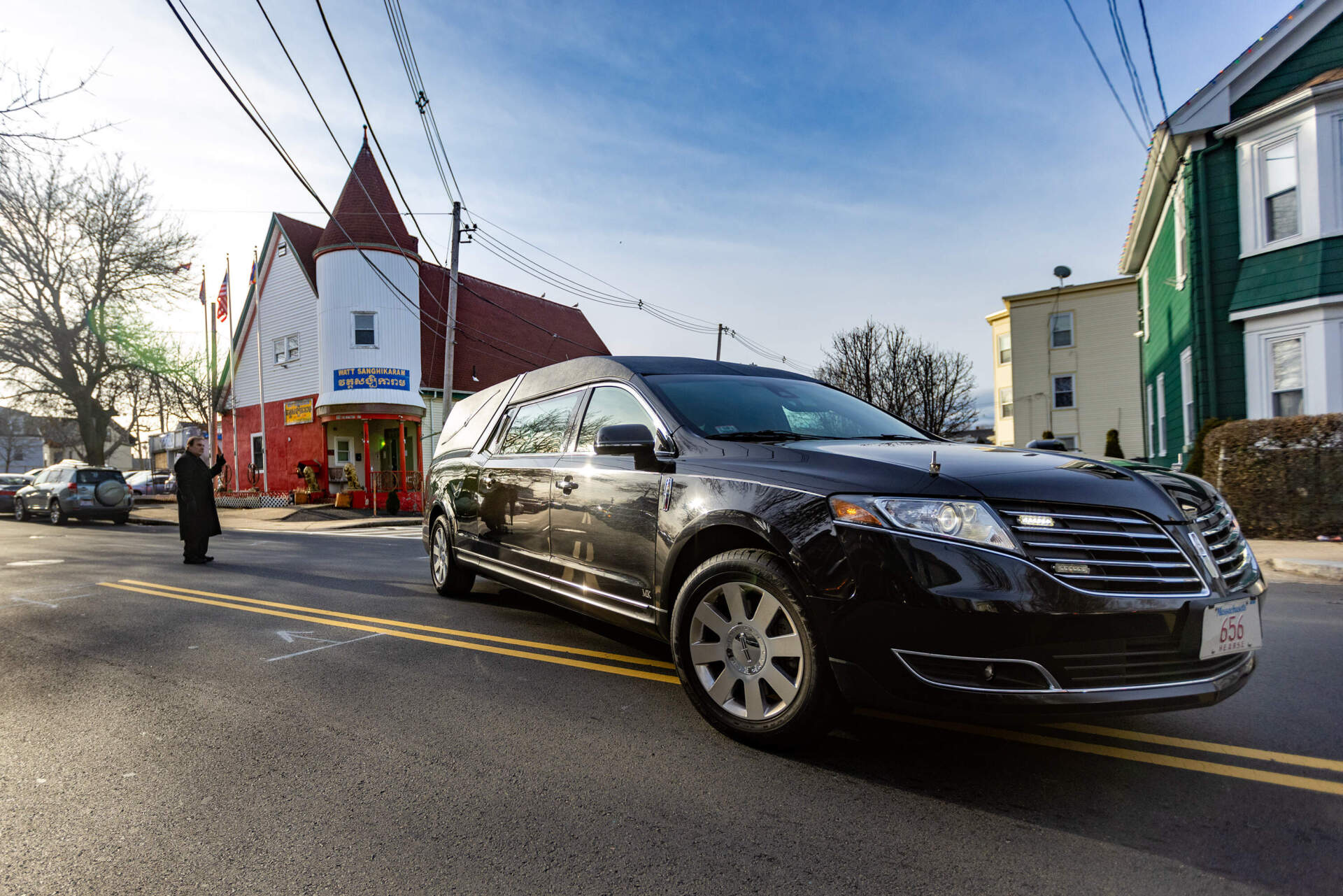 A hearse carrying the body of Kyle Mel leaves the Buddhist Sanghikaram Wat Khmer Temple in Lynn during the funeral procession to Puritan Lawn Memorial Park Cemeteries in Peabody. (Jesse Costa/WBUR)