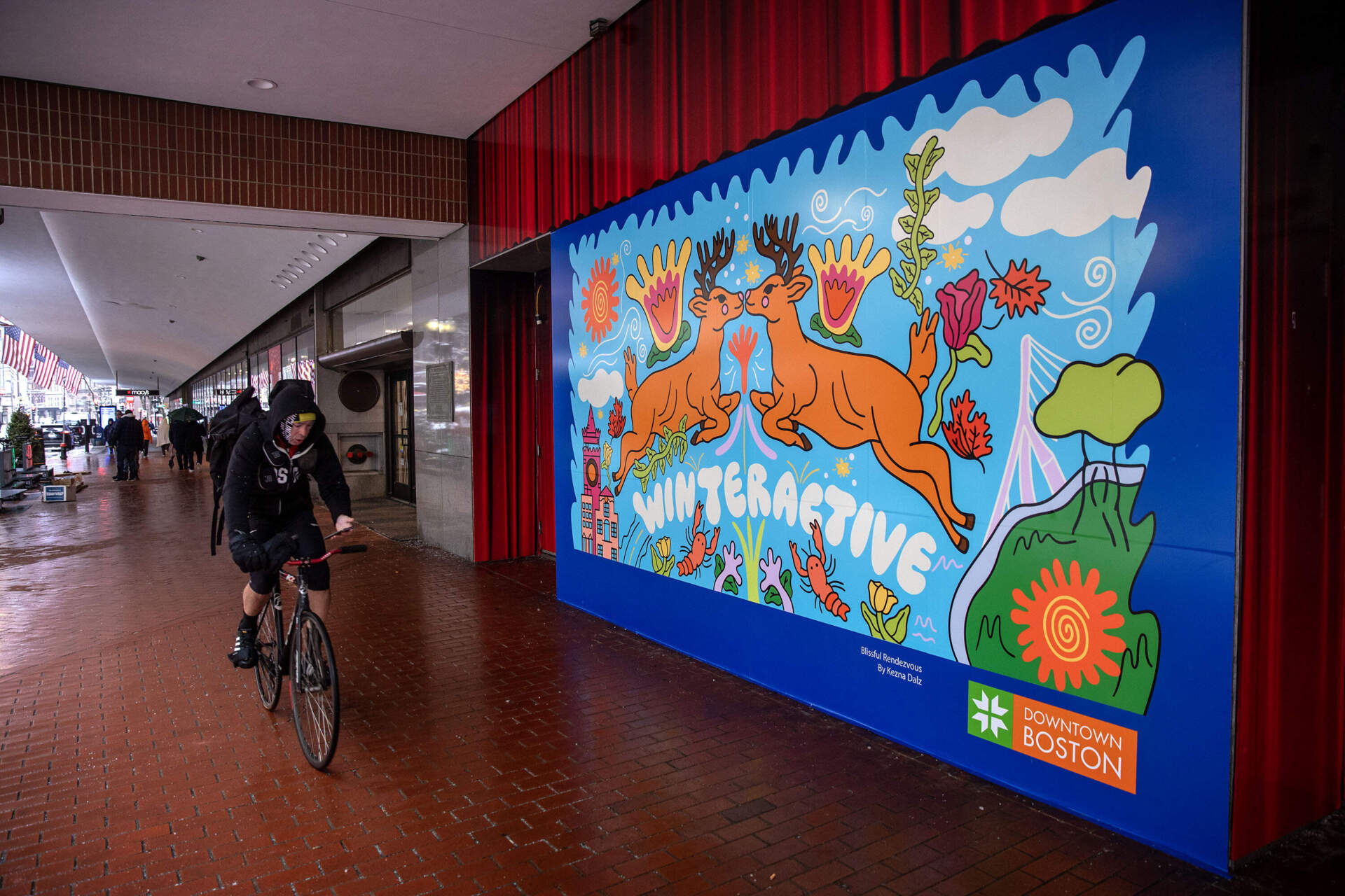 A bicyclist rides past the Winteractive Photo Frame mural on the Summer Street Pedestrian Plaza. (Robin Lubbock/WBUR)