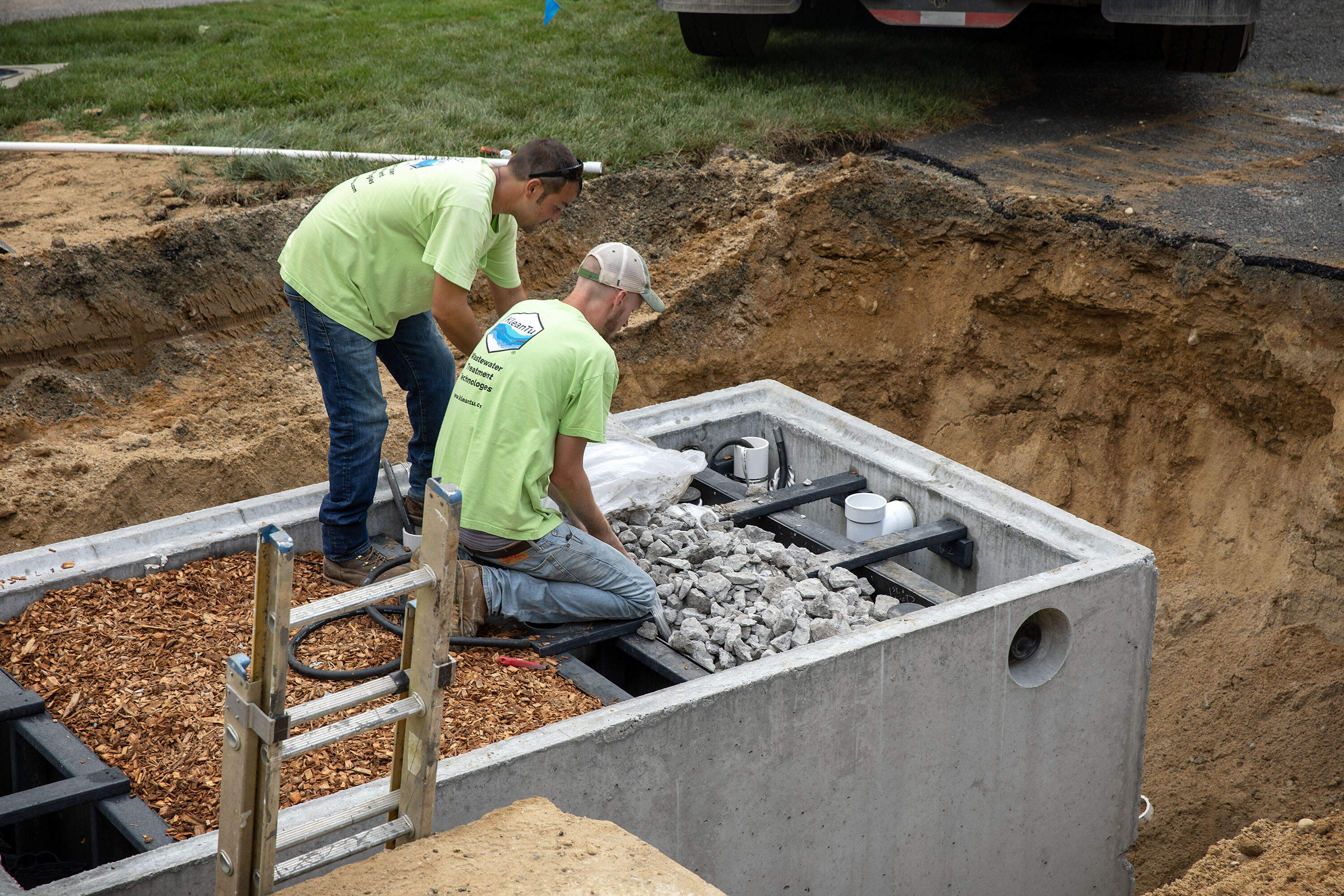 Workers level woodchips and limestone in a denitrification unit, as they work on a septic system in Barnstable, Mass. (Robin Lubbock/WBUR)