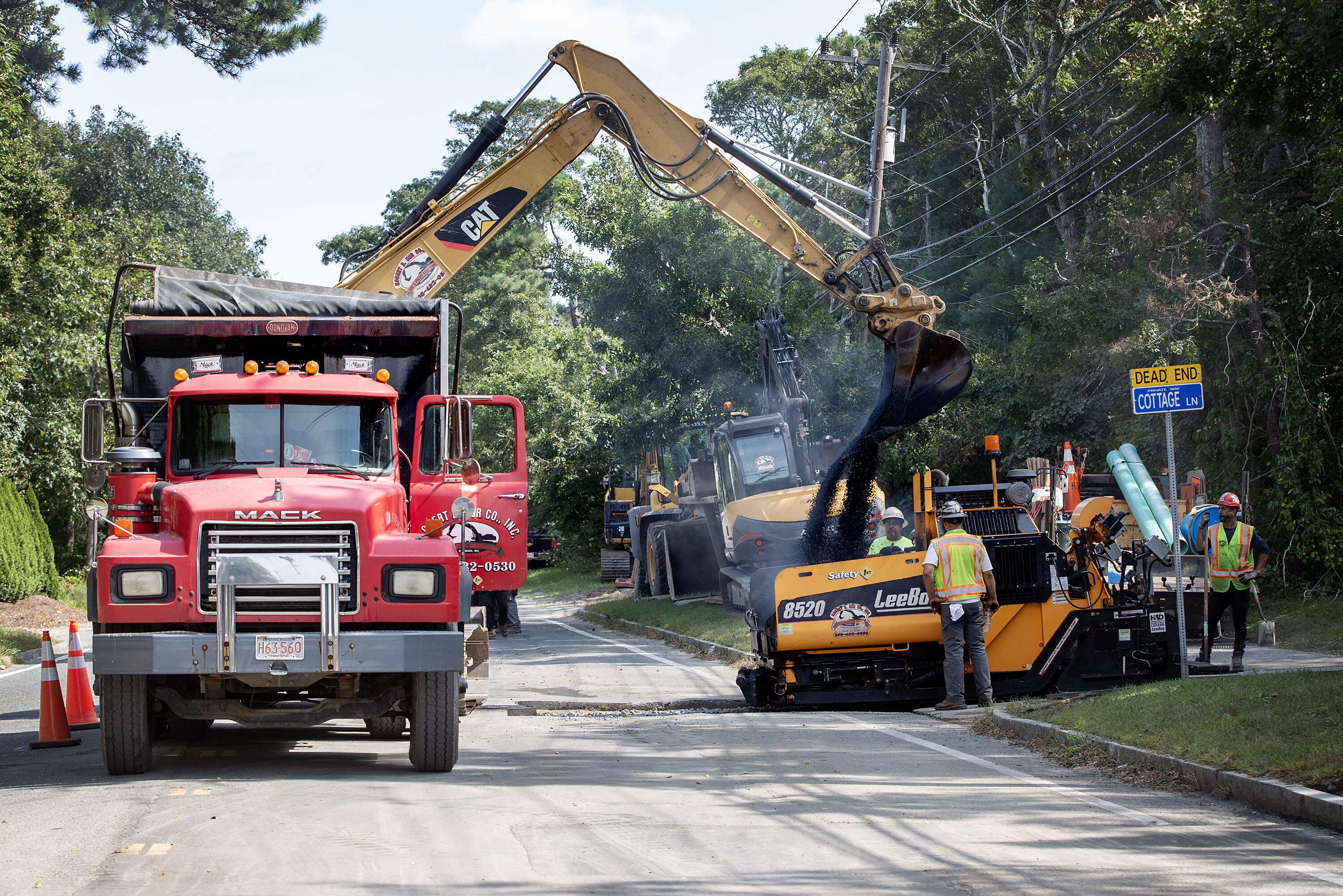 Workers in Barnstable fill in a section of road after laying a new sewer line. (Robin Lubbock/WBUR)