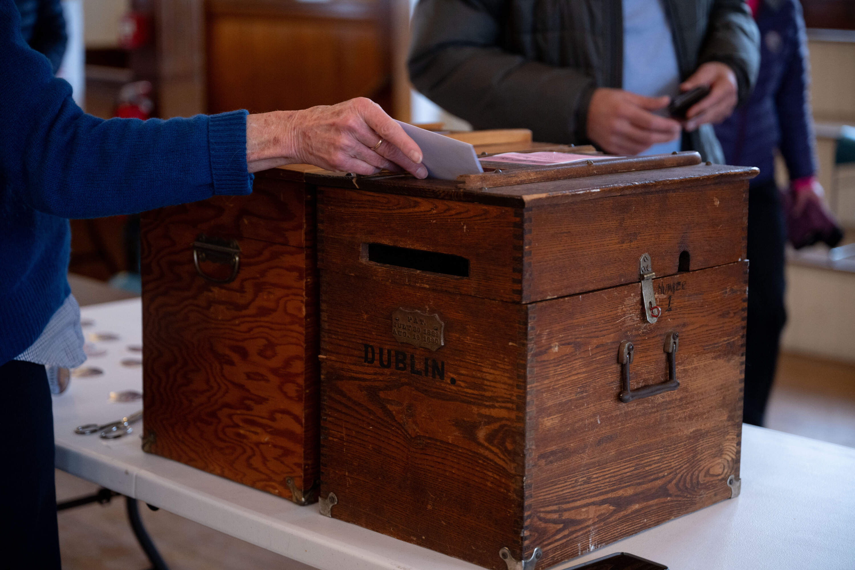 Mary Loftis, 76, an assistant moderator at the Dublin Town Hall polling place, helps voters turn in their ballots. (Raquel C. Zaldívar/New England News Collaborative)