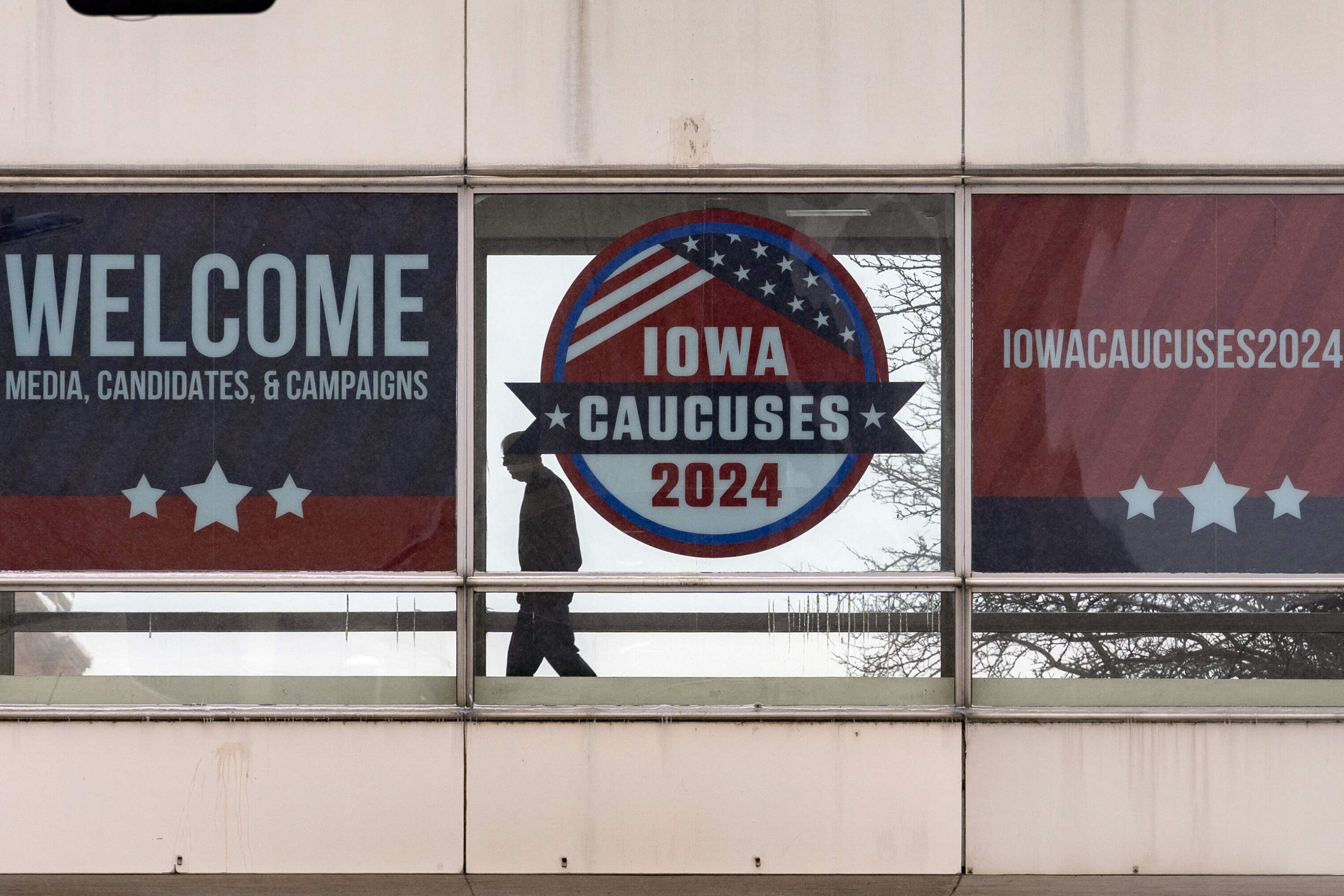 A man walks past a sign that reads "Iowa Caucuses 2024" in downtown Des Moines, Iowa, Saturday, Jan. 13, 2024. (Andrew Harnik/AP)