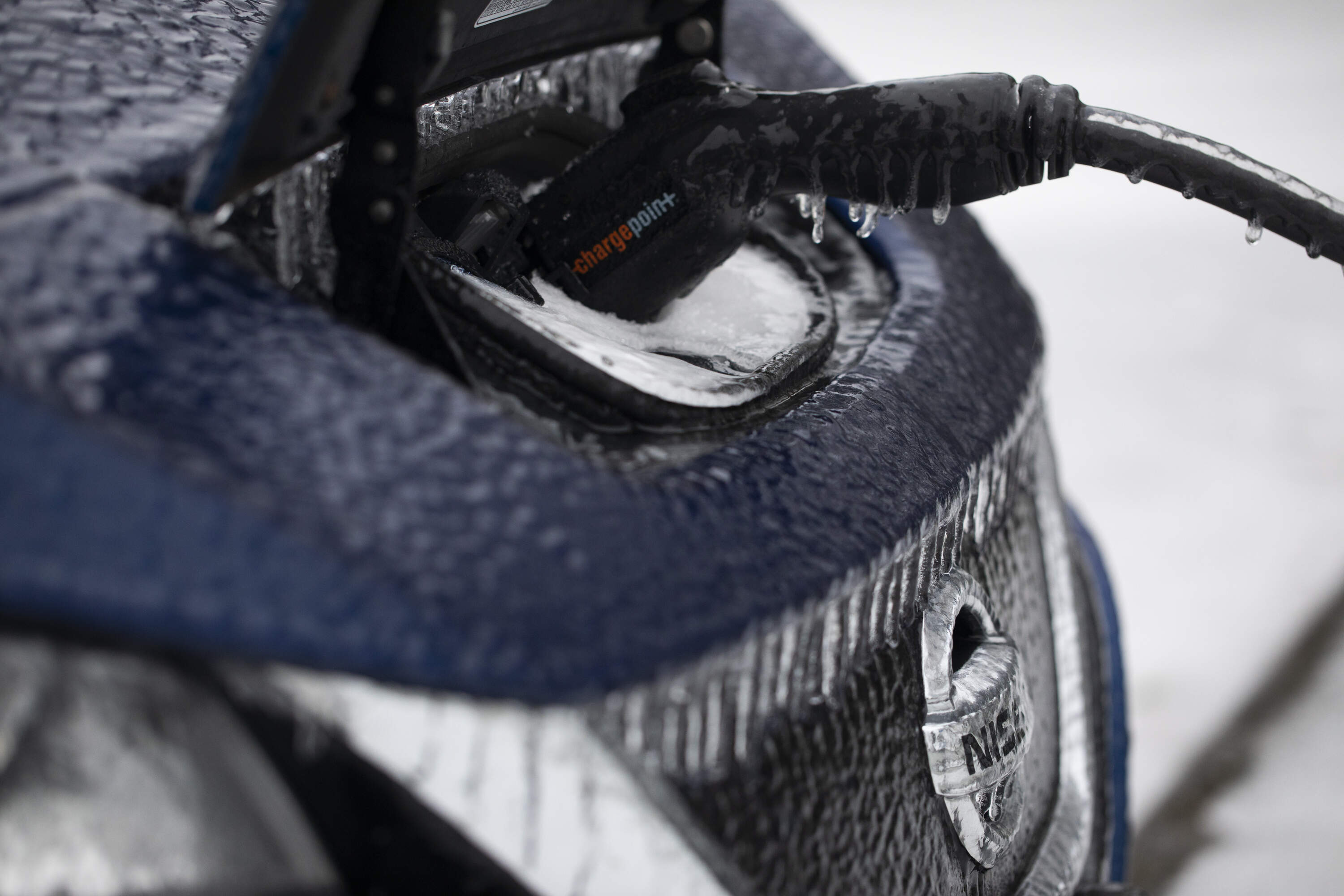 Icicles hang from an electric vehicle that is parked at a charging station. (Jenny Kane/AP)