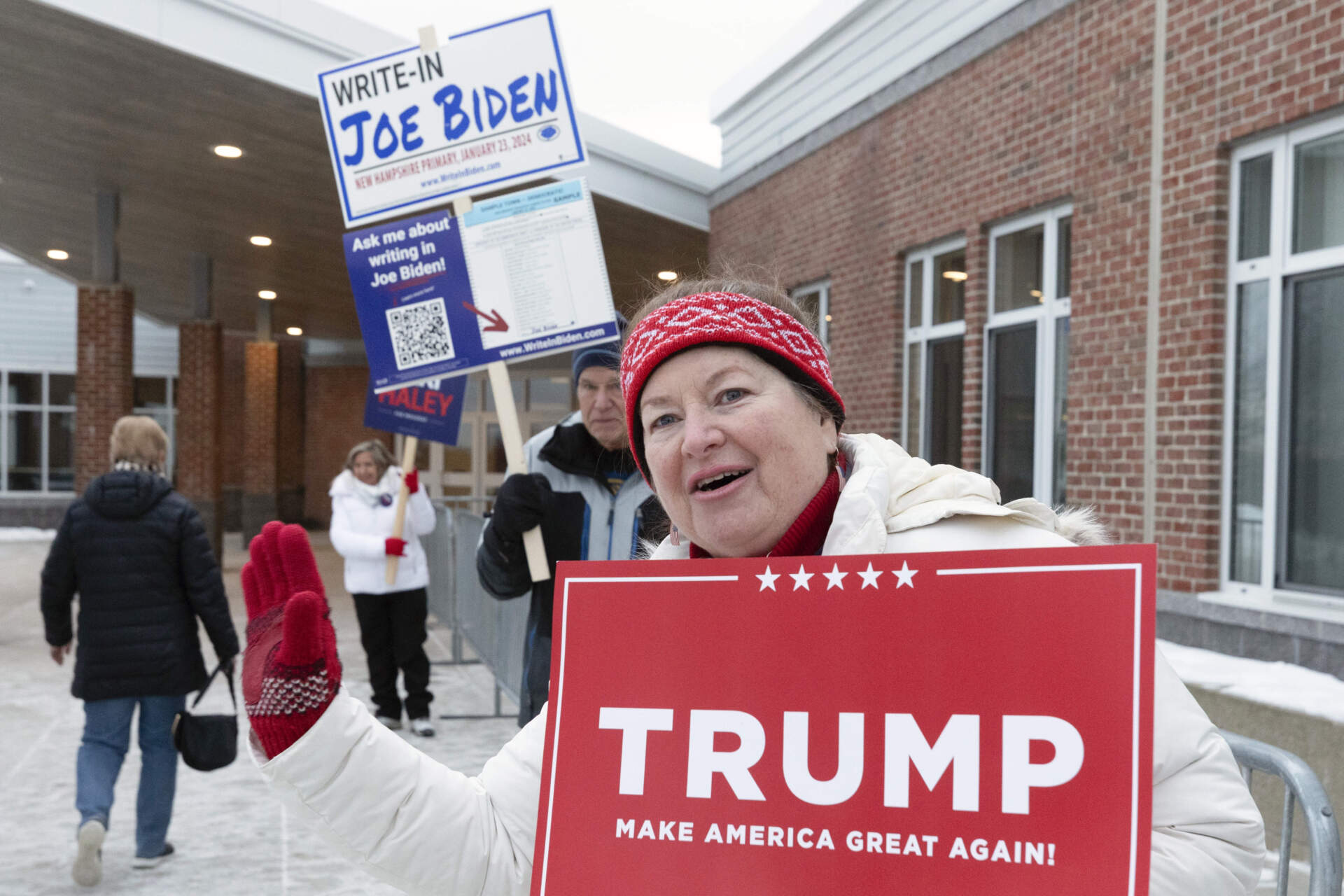 Tina Lorenz, right, and Ed Schoen, behind, hold candidate signs outside the polling place at Windham High School in the presidential primary election, in Windham, N.H. (Michael Dwyer/AP)