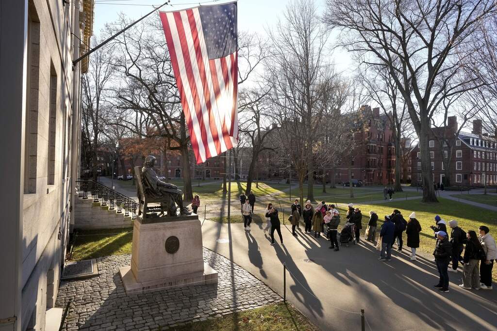 People take photographs near a John Harvard statue, left, Tuesday, Jan. 2, 2024, on the campus of Harvard University, in Cambridge, Mass. Harvard University President Claudine Gay resigned Tuesday amid plagiarism accusations and criticism over testimony at a congressional hearing where she was unable to say unequivocally that calls on campus for the genocide of Jews would violate the school's conduct policy. (Steven Senne/AP)