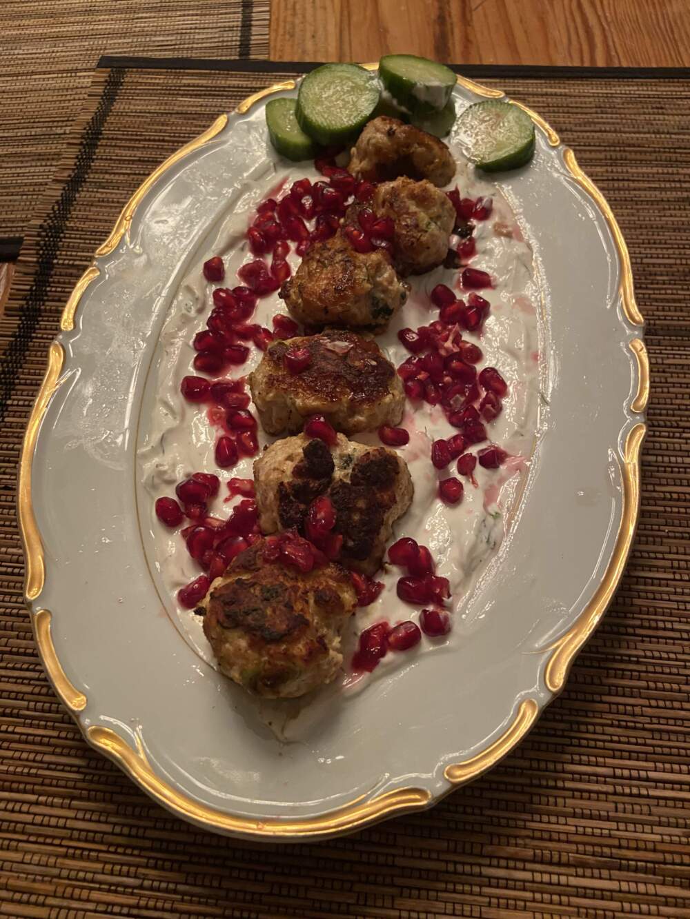Chicken meatballs over Greek yogurt sauce with quick pickled cucumbers and pomegranate seeds. (Kathy Gunst/Here & Now)