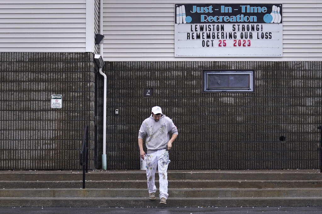 A painter passes a "Lewiston Strong!" sign displayed outside the Just-In-Time bowling alley while taking a break from renovating. (Charles Krupa/AP)