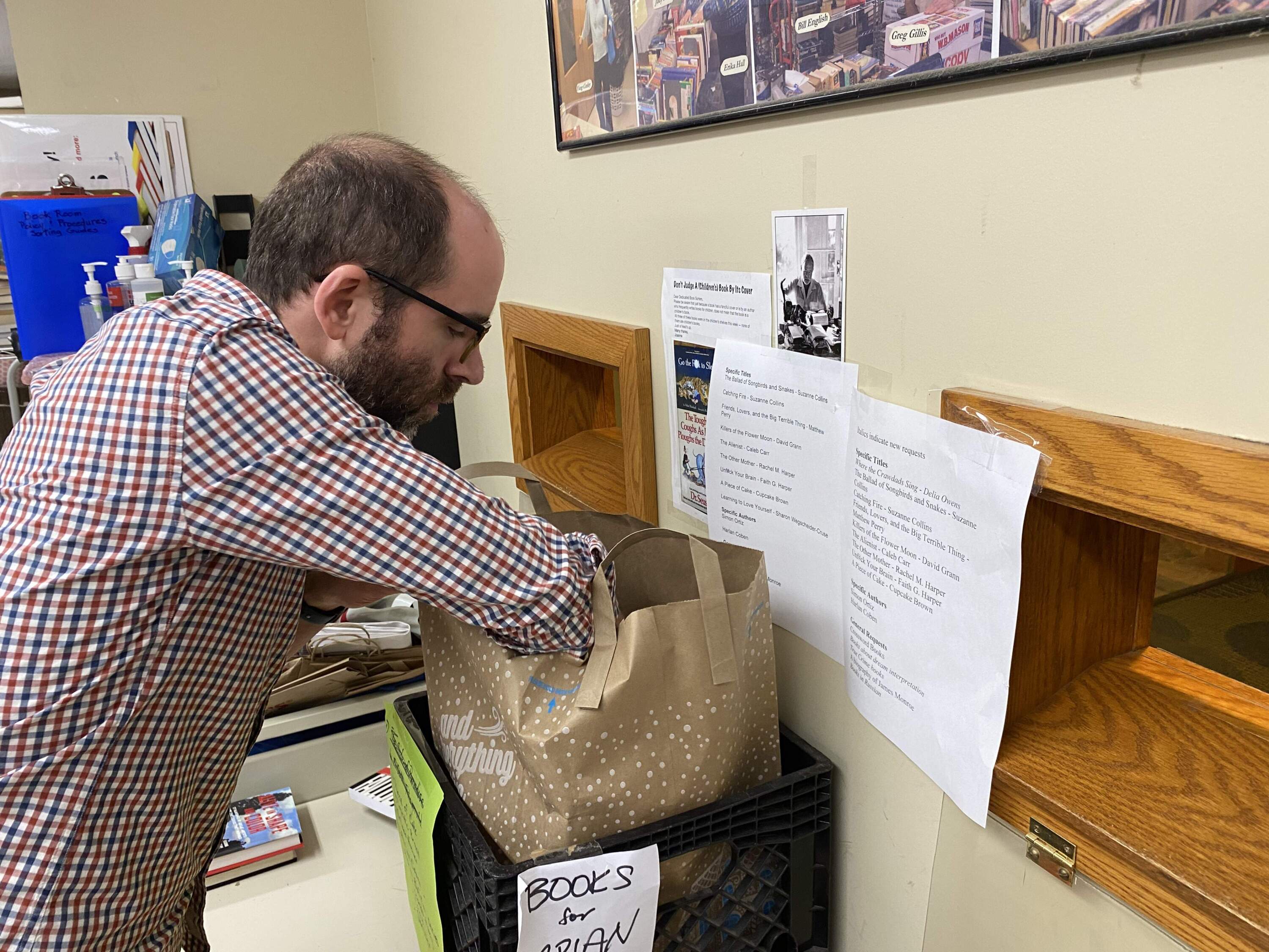 Brian Stokes peeks at books designated for inmates at the Barnstable County jail. (Simón Rios/WBUR)
