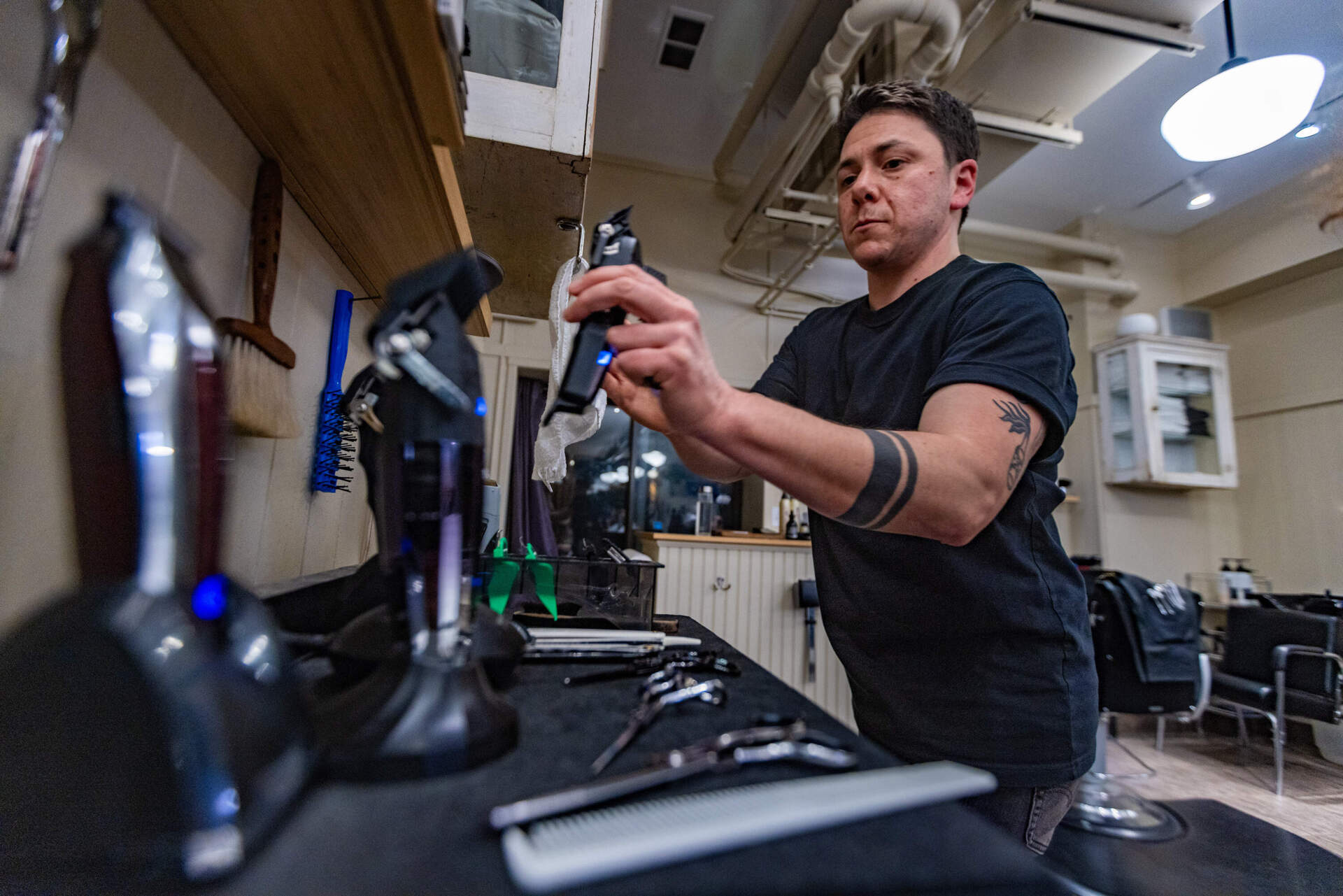 M Arida grabs a pair of hair clippers before working on a client. (Jesse Costa/WBUR)