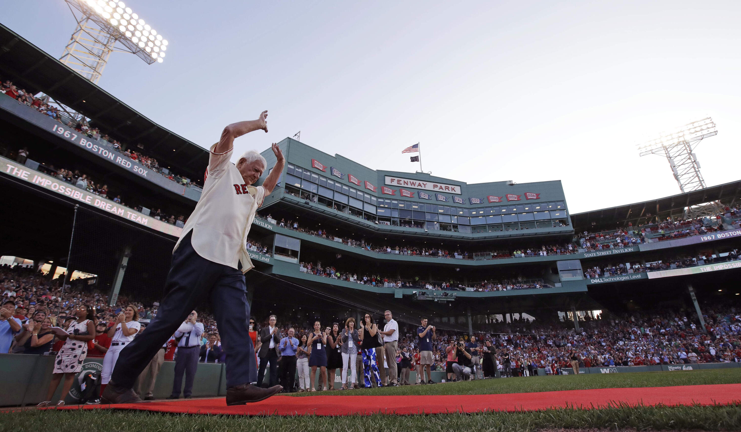 Boston Red Sox great Carl Yastrzemski raises his arms as he is honored with teammates on the 50th anniversary of the 1967
