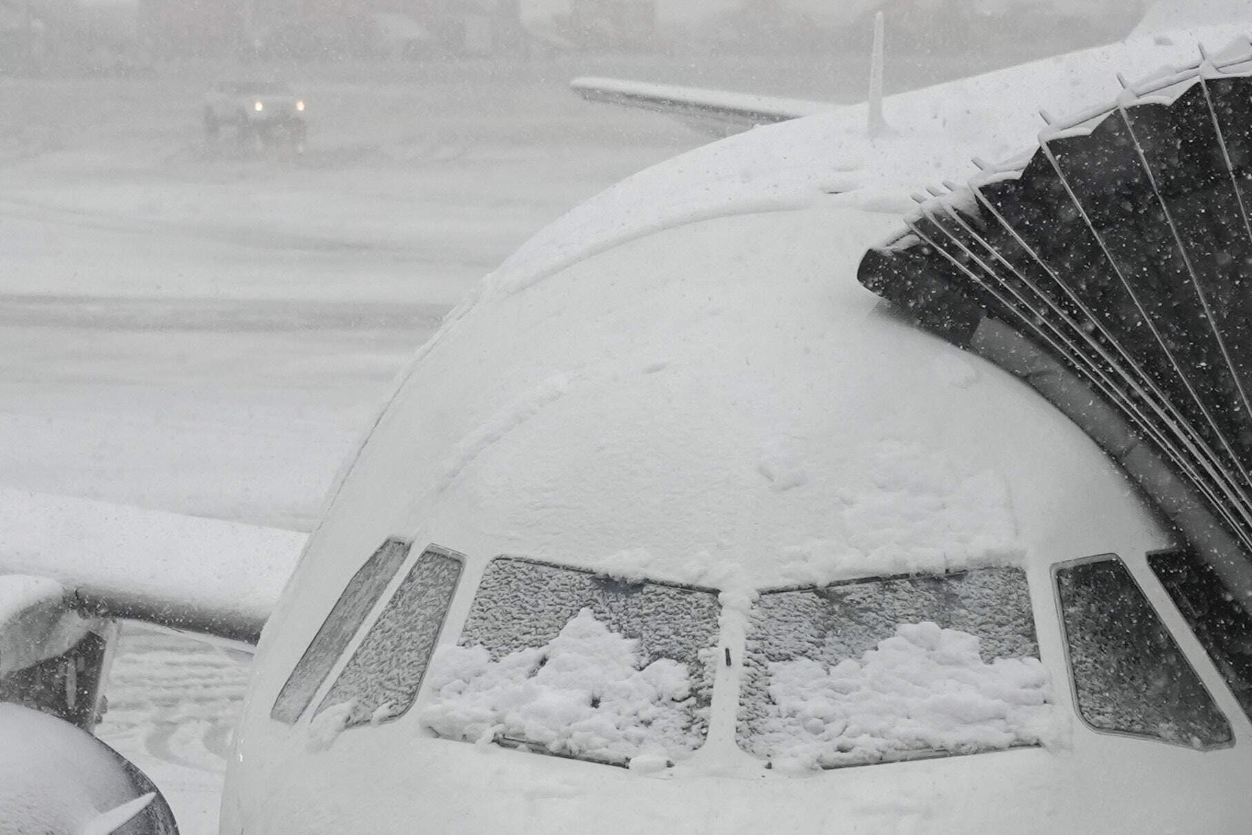 Snow covers the windows of a plane that sits at a gate at JFK Airport on Tuesday in New York. (Frank Franklin II/AP)