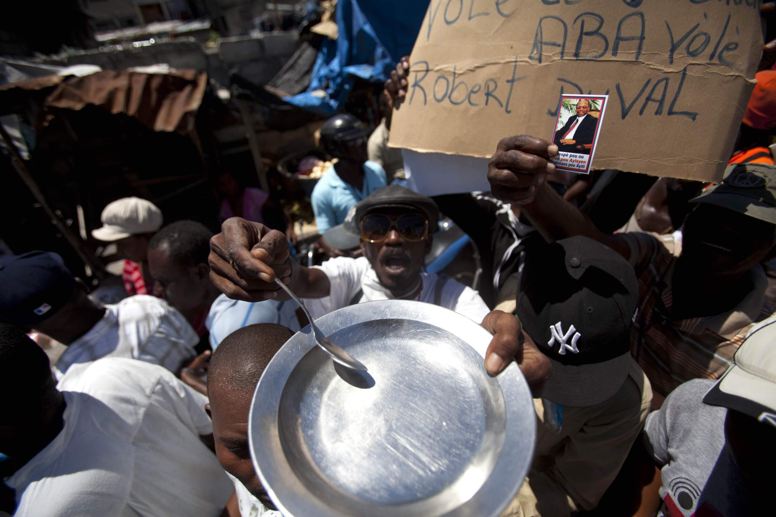 A protester holding an empty plate and a spoon chants anti-government slogans during a demonstration marking the 27th anniversary of the signing of Haiti's Constitution, in Port-au-Prince, Haiti, Saturday, March 29, 2014. (Dieu Nalio Chery/AP)