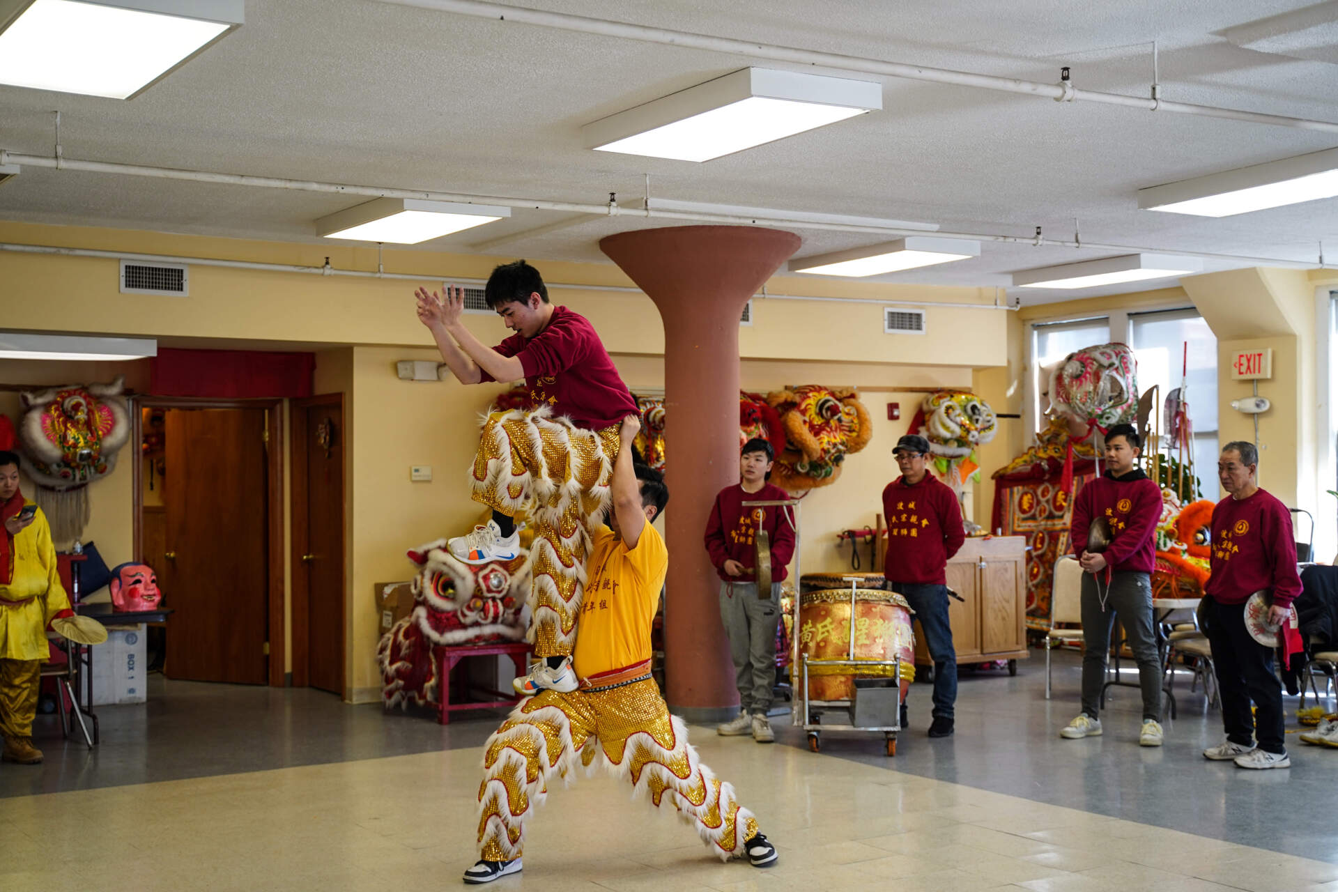 In the Boston Wong Family Benevolent Association space, Lucas Wang practices lifting Henry Chen. (Cici Yu/ WBUR)