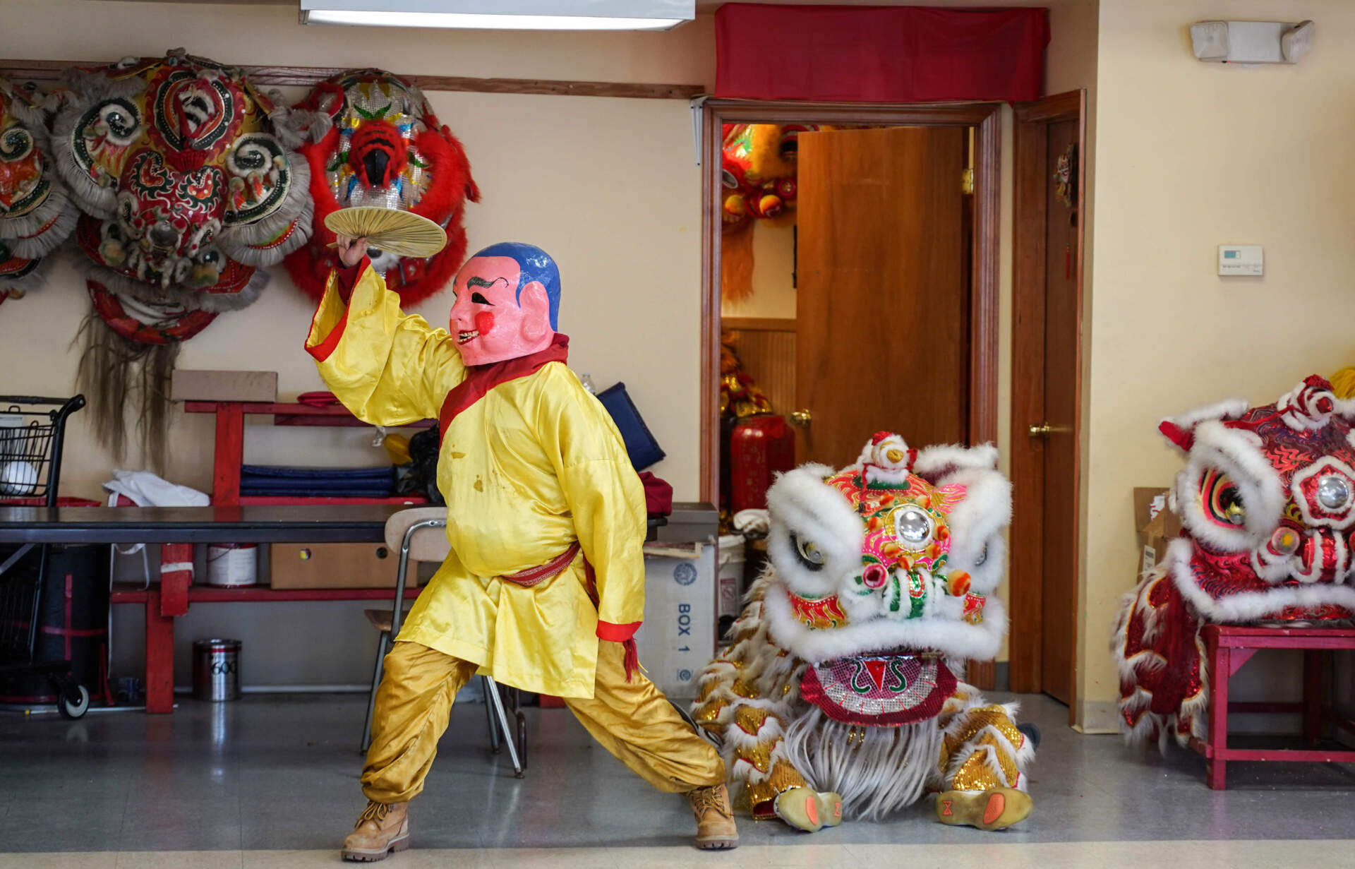 A Buddha introduces a lion to the stage in a parade rehearsal at the Boston Wong Family Benevolent Association practice room. (Cici Yu/WBUR)