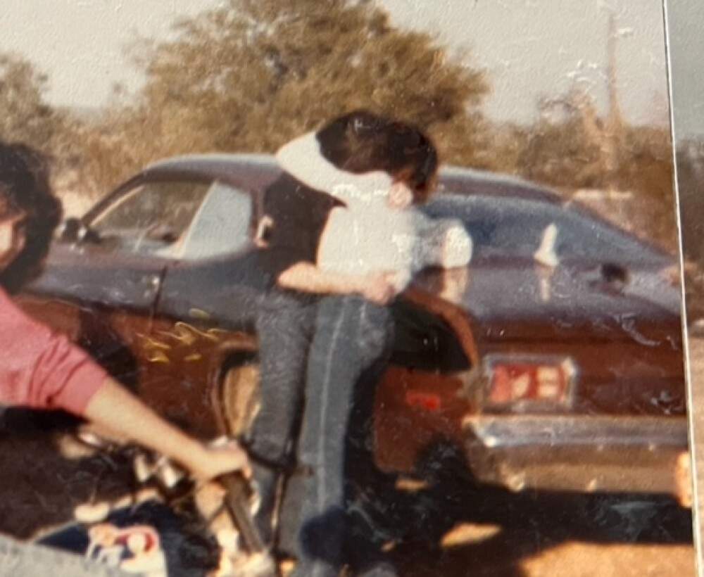 "I did not come from a fast car family," writes Susan Donovan Bernhard, "but I came of age around fast car boys who drag raced on quarter-mile stretches of highway." One of those fast car boys shared this photo of his cousin in an embrace in front of his 1975 Duster. (Courtesy Susan Donovan Bernhard)