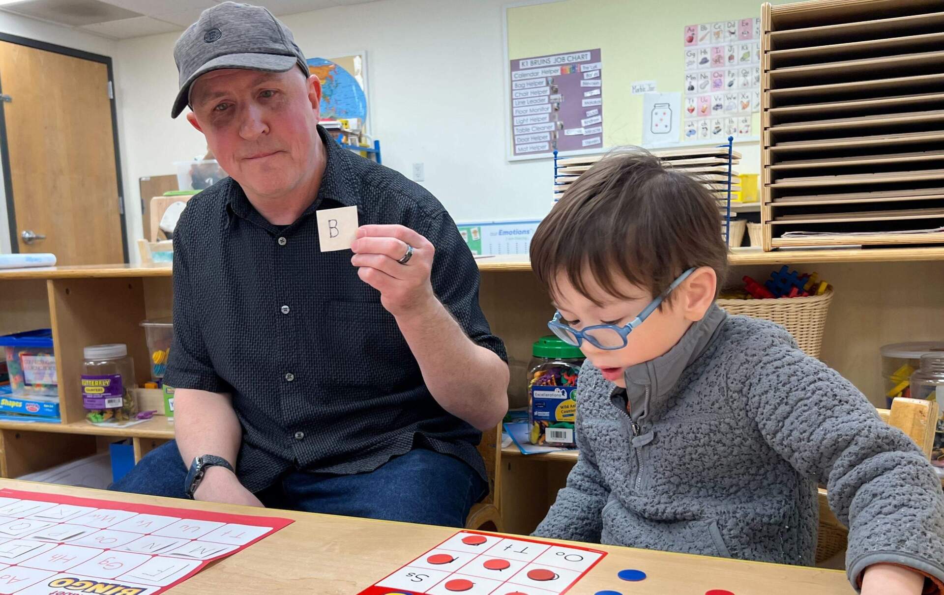 Matthew Wallace does a bingo activity with a student. (Ashley Locke/Here &amp; Now)