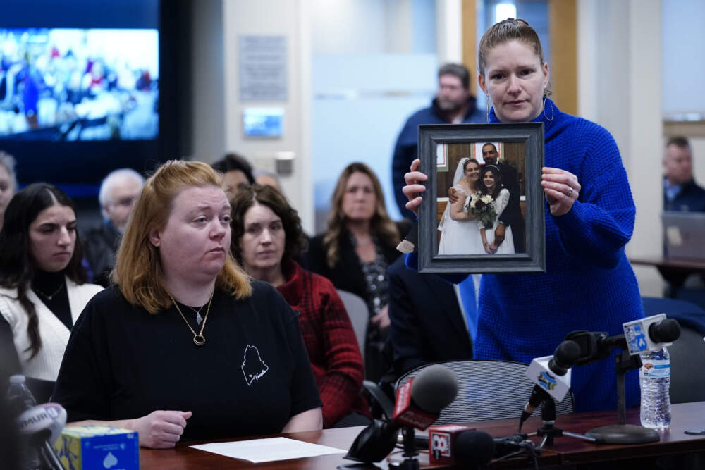 Elizabeth Seal holds a photo from Megan Vozzella's wedding to Steve Vozzella during a hearing of the independent commission. (Robert F. Bukaty/AP)