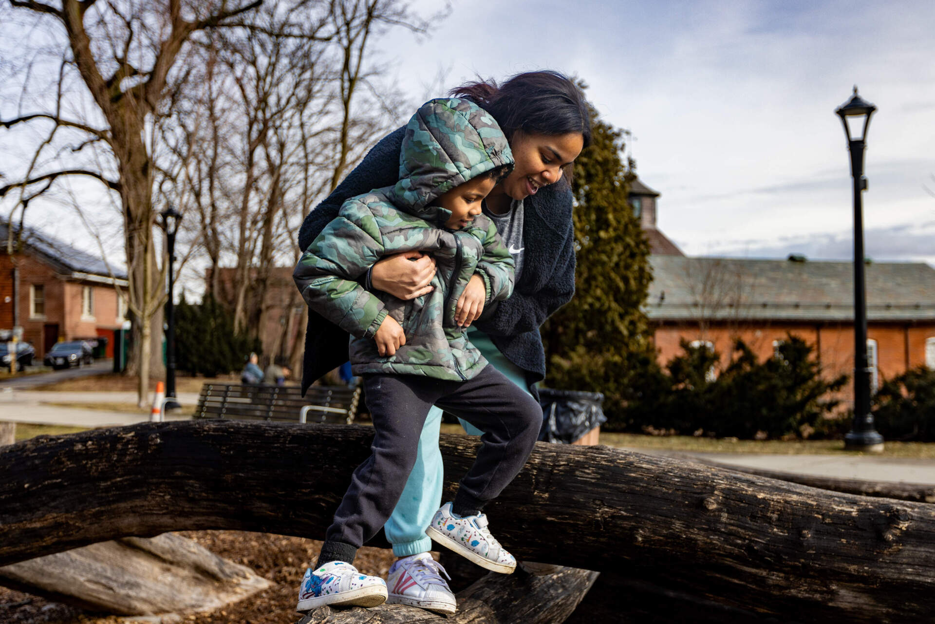 Graciella Carter and her son Oscar climb on logs at a Northampton park. (Jesse Costa/WBUR)