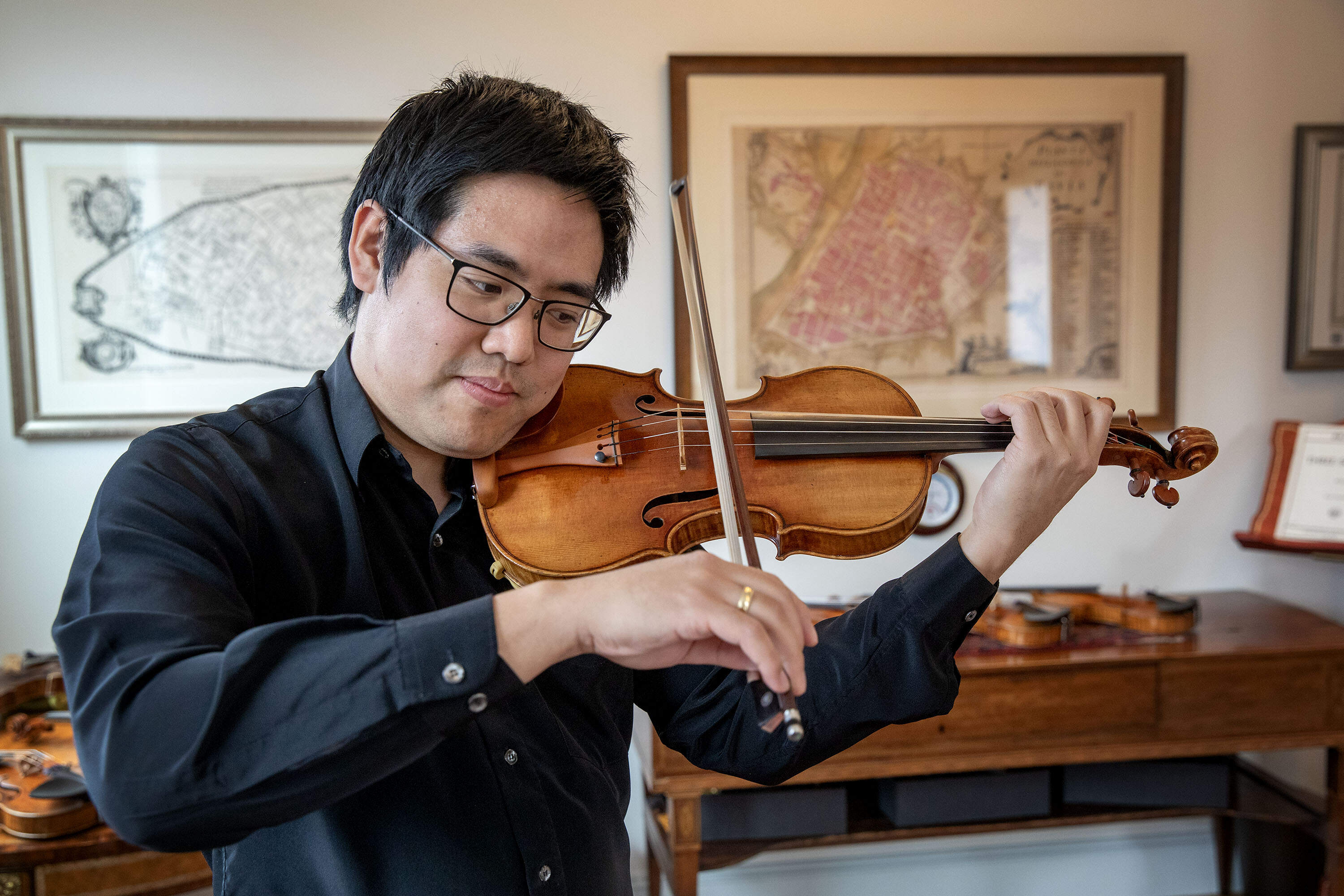 Violinist Zenas Hsu listens carefully to the Antonio Stradivari violin he's playing. (Robin Lubbock/WBUR)