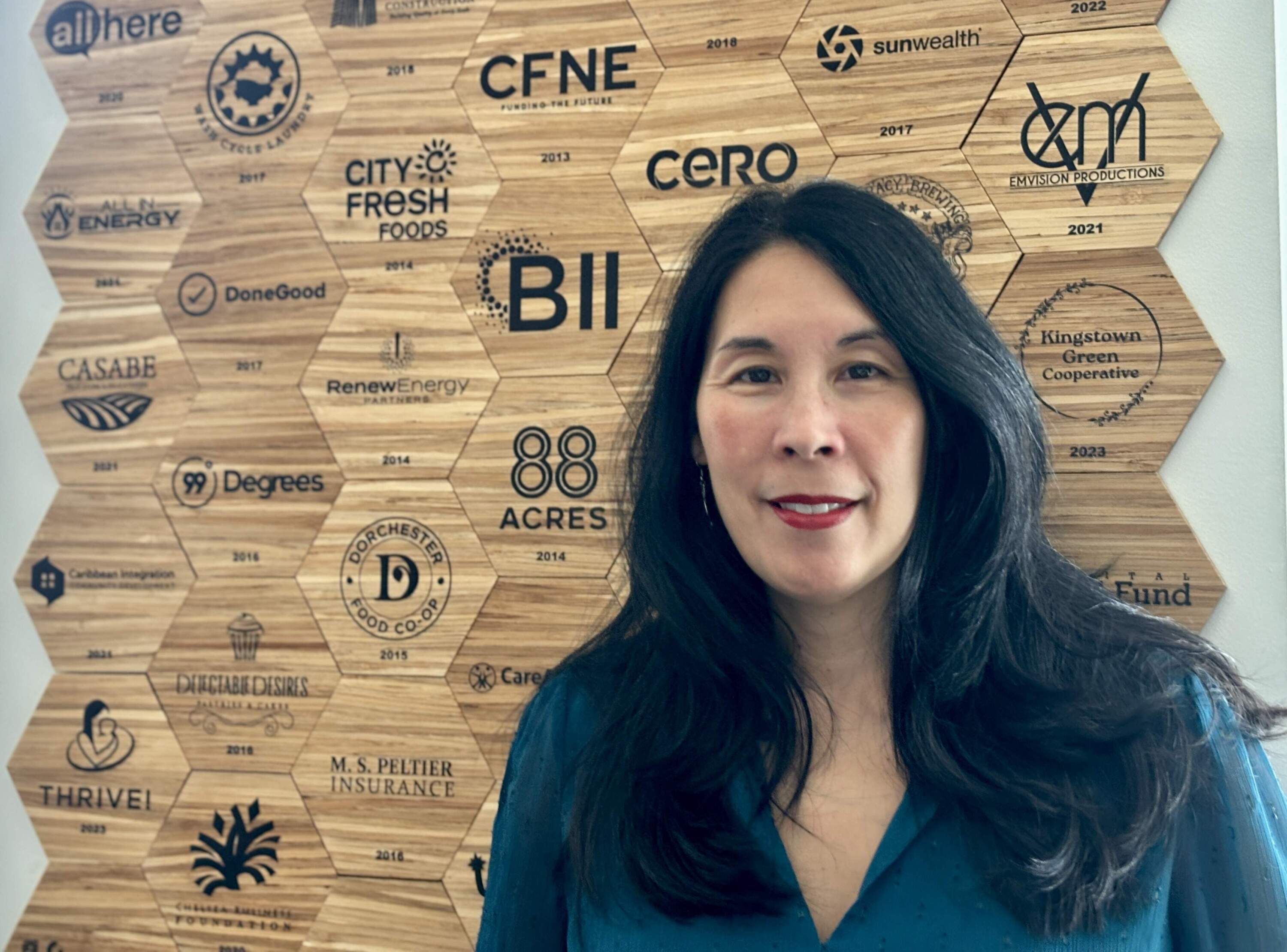 CEO Betty Francisco stands in front of a wall with names of businesses the Boston Impact Initiative has invested in. (Photo courtesy Betty Francisco)