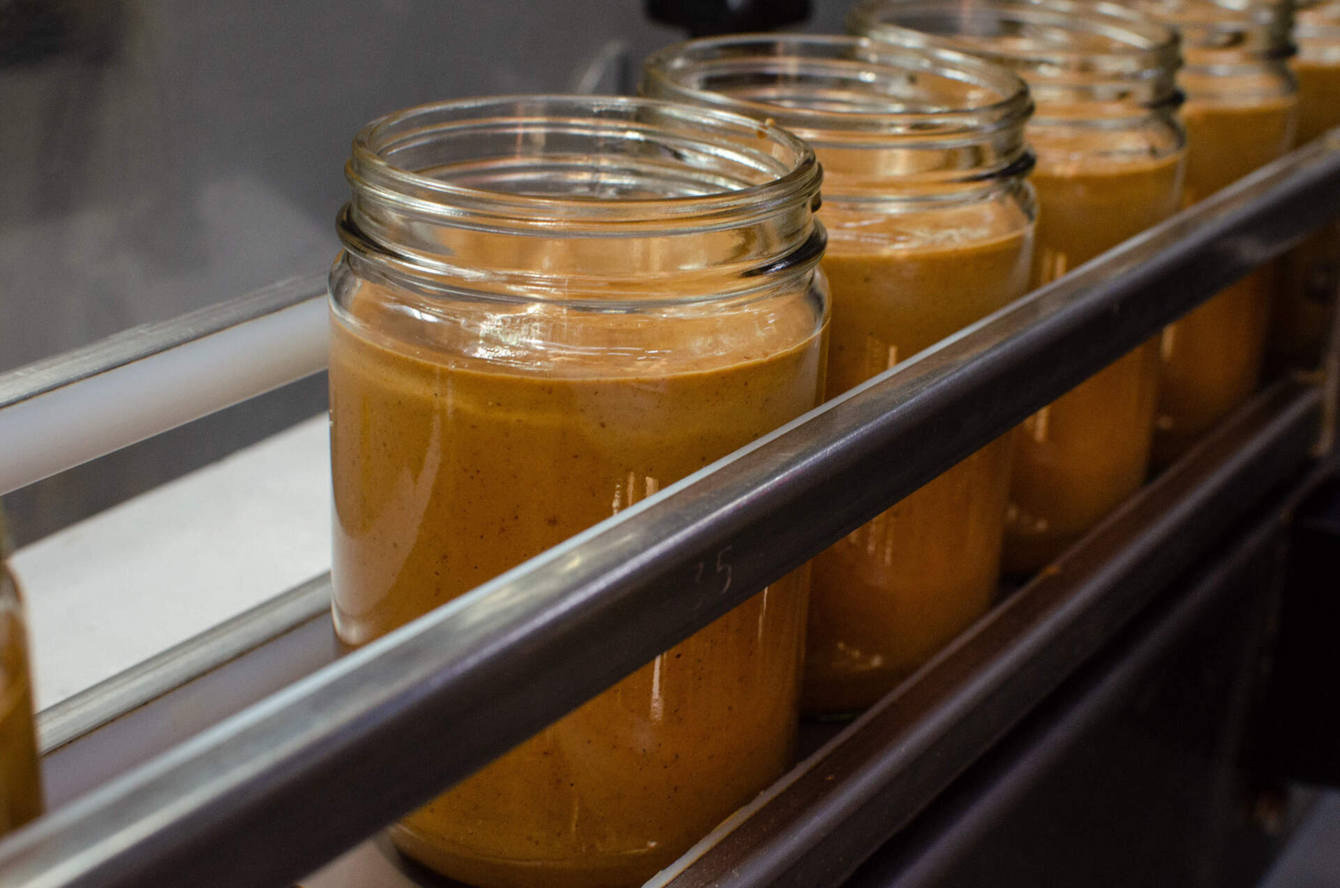 Teddie natural smooth peanut butter in jars awaiting lids and labels. (Sharon Brody/WBUR)