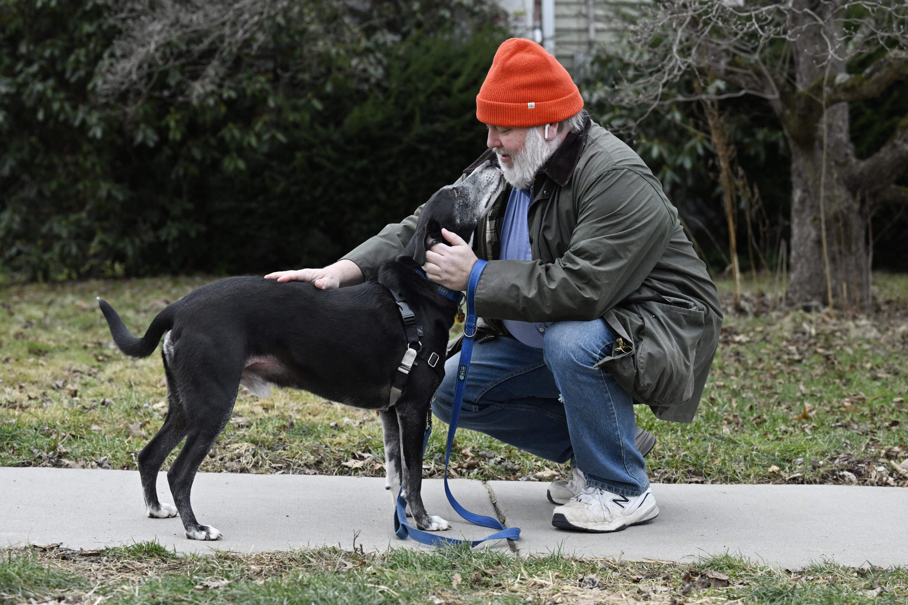 Casey Rosseau wears earbuds to listen to an e-book when he walks his dog Darcy in West Hartford, Conn. (Jessica Hill/AP)