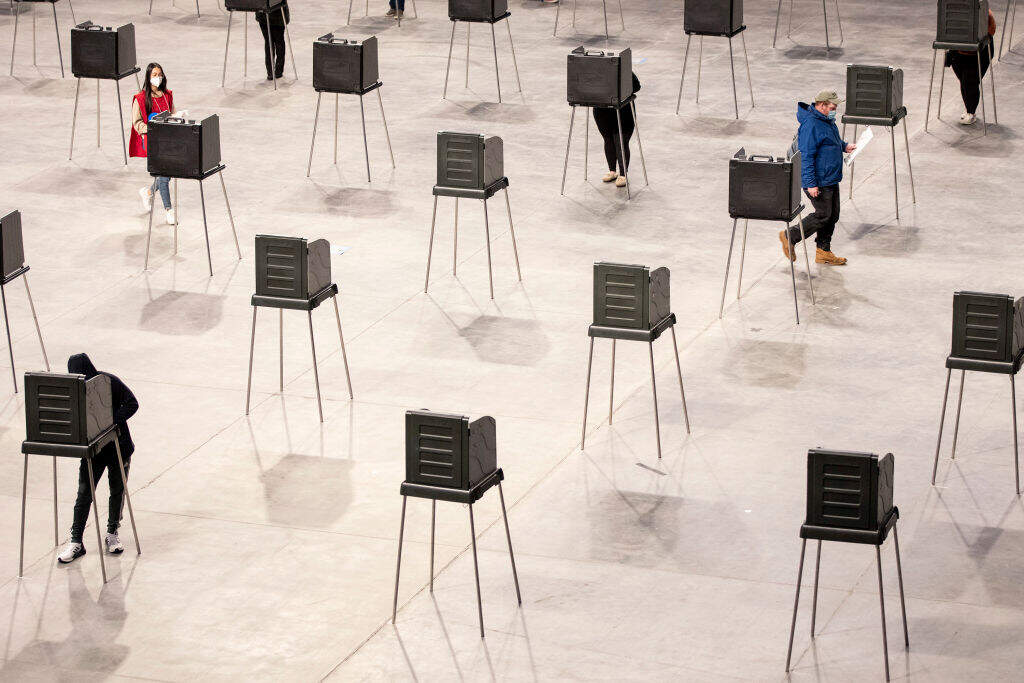 A poll worker walks over to sanitize a voting booth after a voter leaves to walk their ballot over to the machines at Cross Insurance Center on Tuesday, November 3, 2020. (Brianna Soukup/Portland Press Herald via Getty Images)