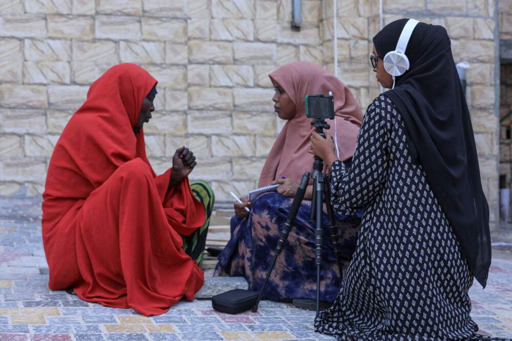 Two female journalists working for Bilan Media, a Somali start-up staffed entirely by women, interview a woman running a restaurant in a market in Mogadishu on May 22, 2022. (Hasan Ali Elmi/AFP via Getty Images)