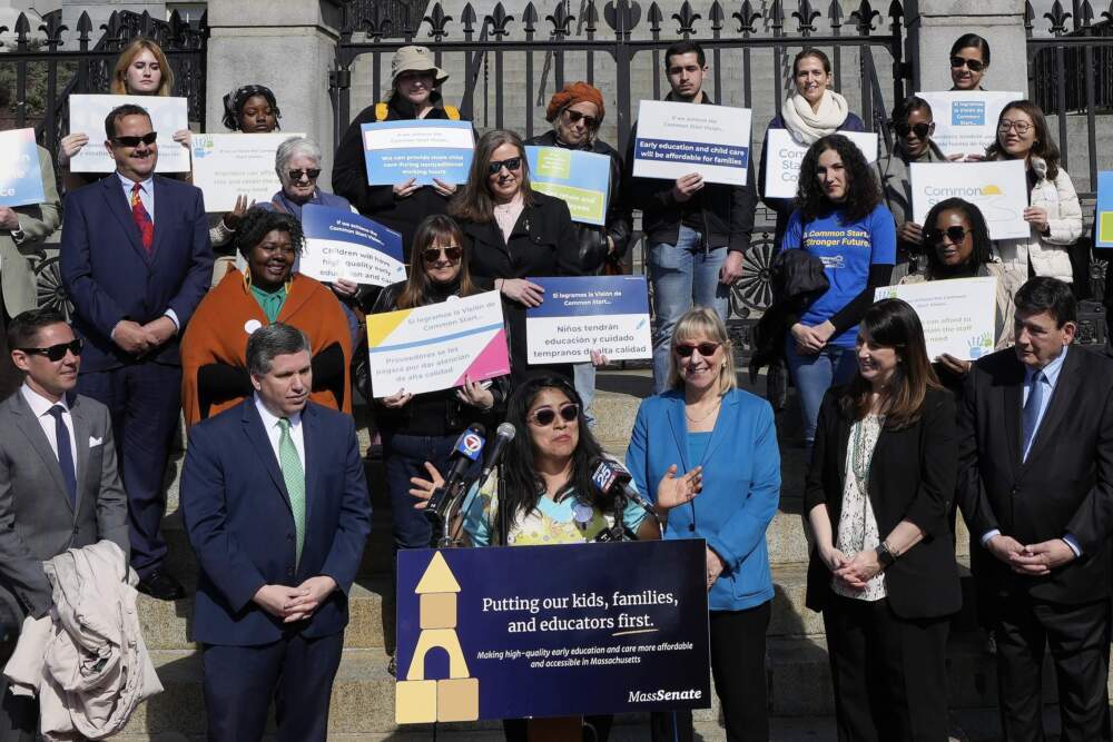 Alejandra De La Cruz, at the podium, who is a lead toddler teacher at Ellis Early Learning, speaks during a rally outside the State House, Thursday, March 14, 2024, in Boston. (Michael Dwyer/AP)