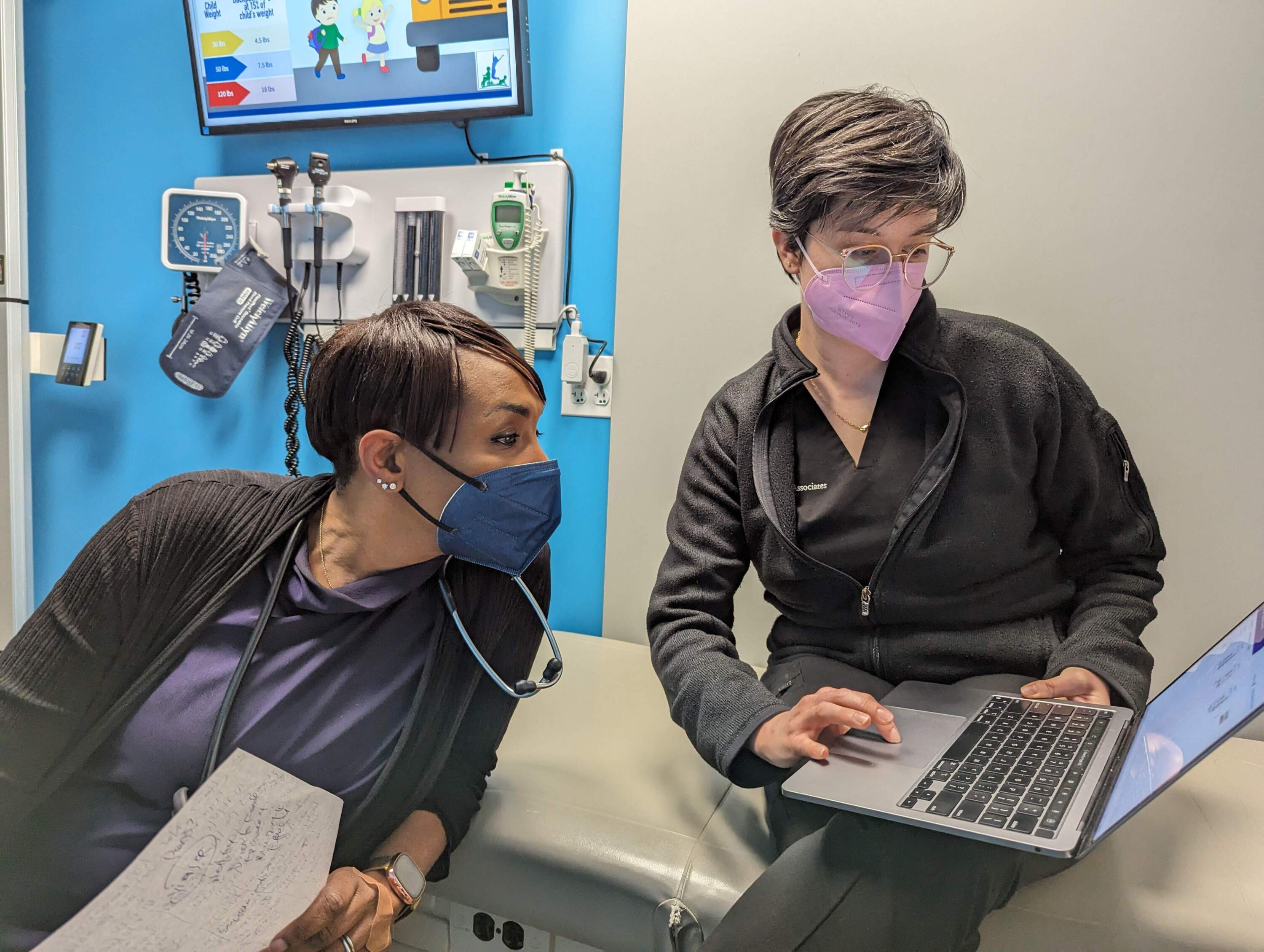 Dr. Chloe Campbell and medical assistant Sydney Le Lannic check the calendar to find an appointment for a young patient. (Priyanka Dayal McCluskey/WBUR)