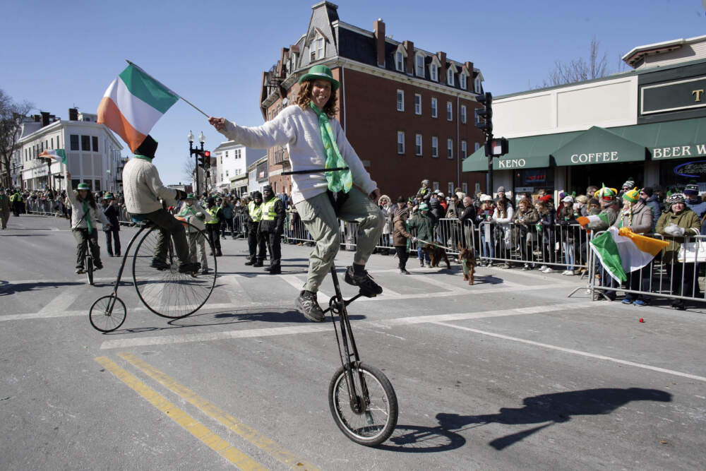 A member of the Cycling Murrays holds an Irish flag while riding a unicycle during the annual St. Patrick's Day parade in 2018. (Steven Senne/AP)