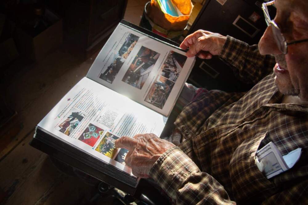 Floyd Van Alstyne flips through a binder full of family history. Van Alstyne has lived in Vermont for several decades. (Elodie Reed/Vermont Public)