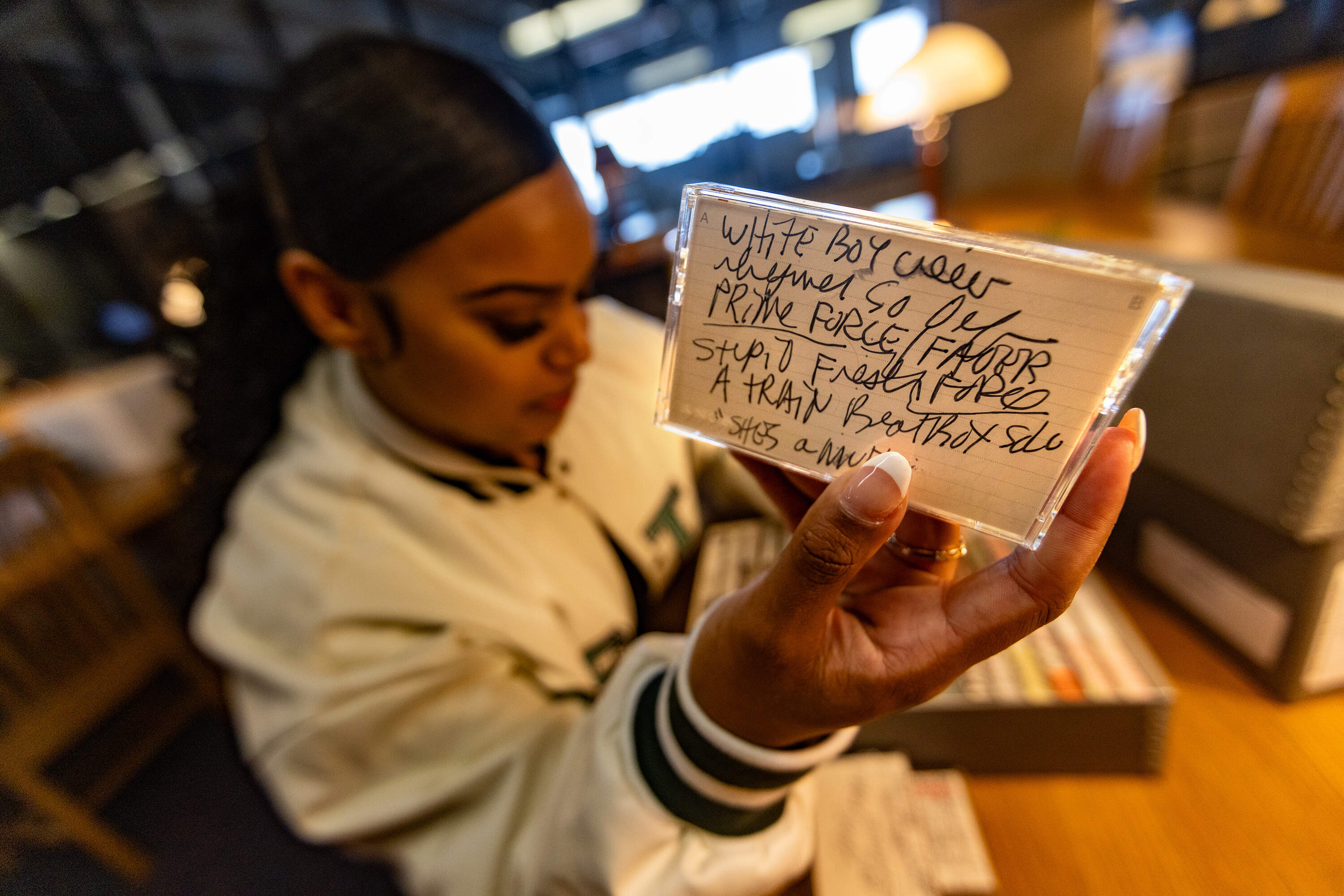 Ebony Gill holds up a hip-hop cassette tape from the 1990s as she does research at the Healey Library at UMASS Boston. (Jesse Costa/WBUR)