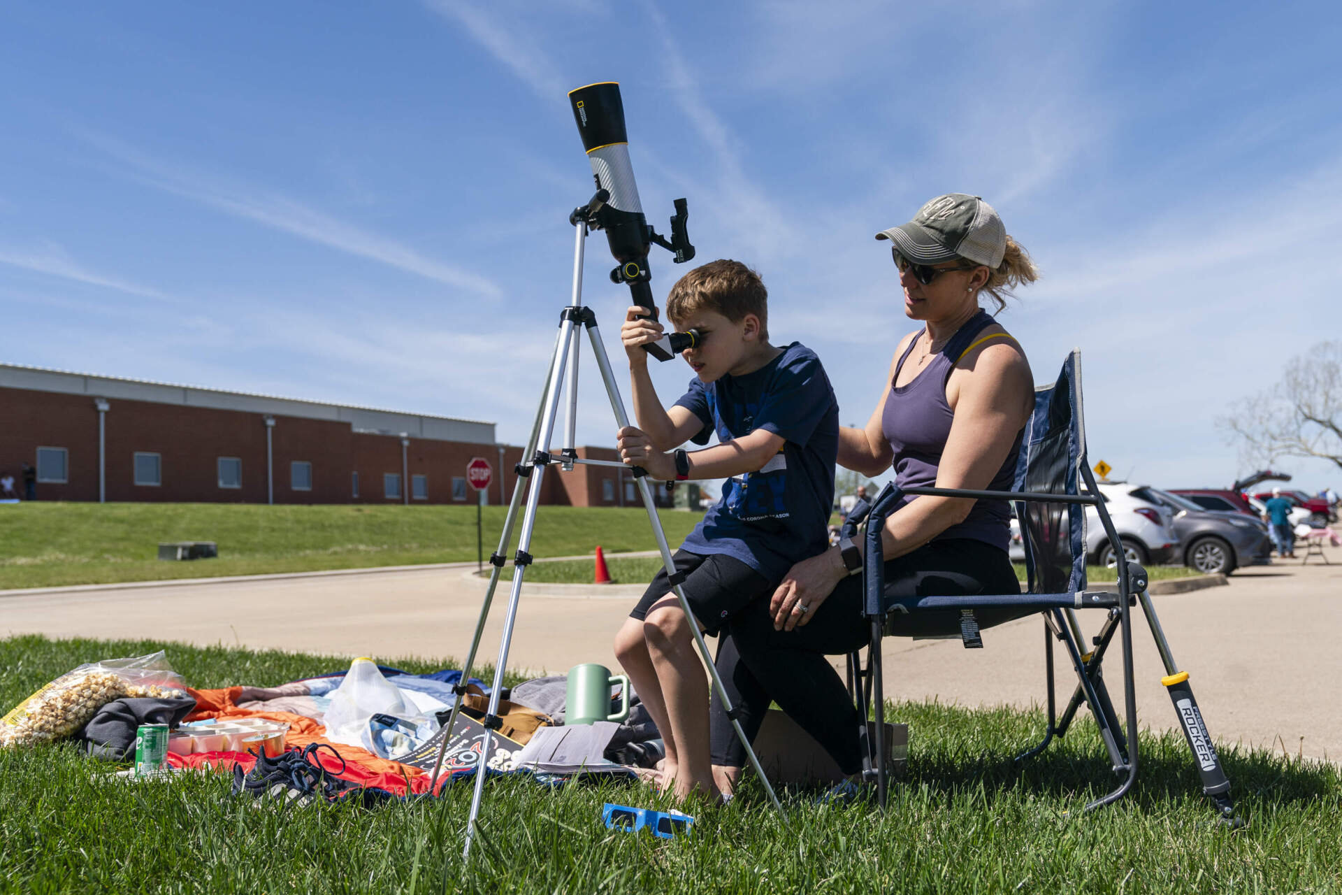 Anne Flanagan, 41, helps her son, Patrick Flanagan, 8, as they look for the sun through a telescope during an event for the solar eclipse. (Eric Lee/STLPR)