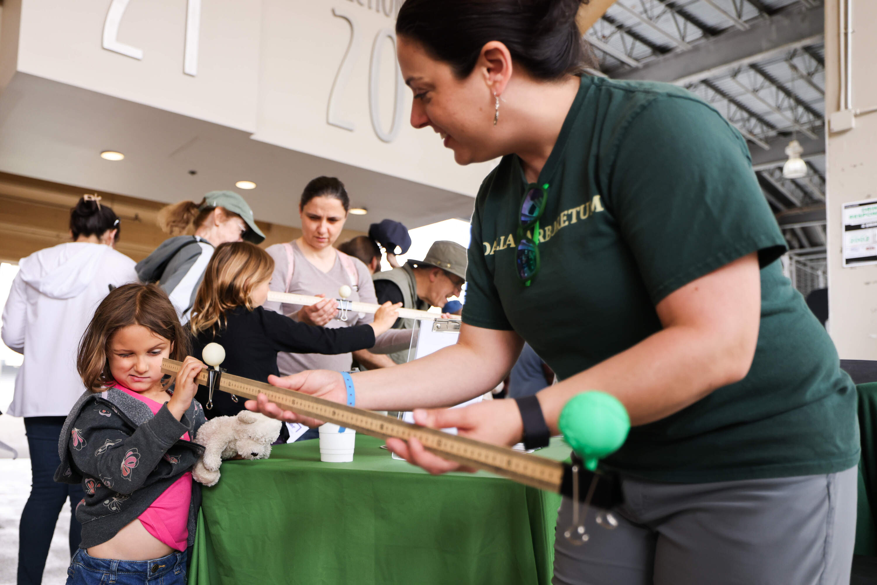 Amy Nickell with Dallas Arboretum helps Dani Turin, 5, look down the ruler at the sun and the moon to see the perspective of the eclipse Monday, April 8, 2024, at Cotton Bowl in Dallas. (KERA Texas)