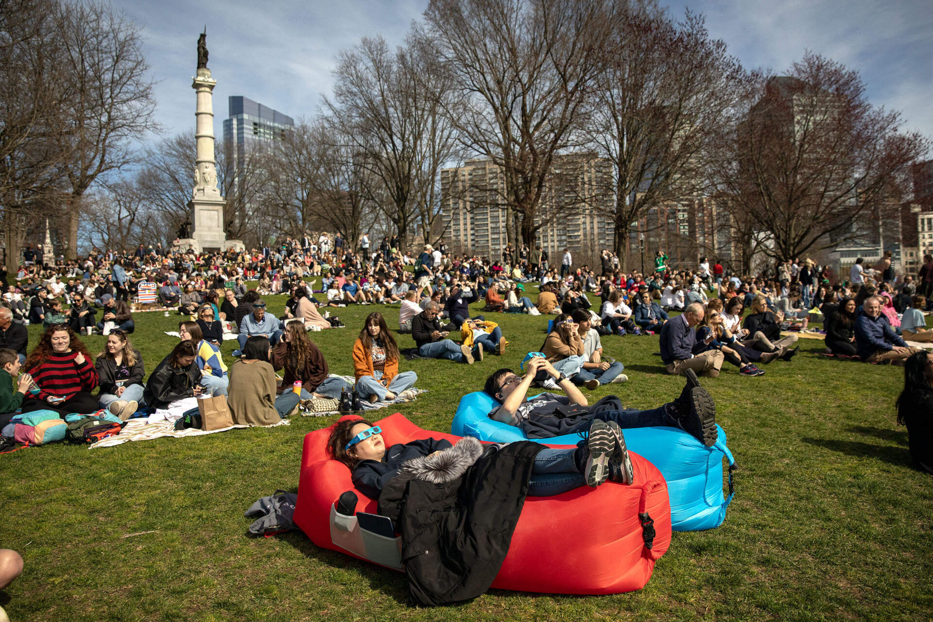 Some eclipse watchers lounge on Boston Common watching the eclipse come into its peak. (Robin Lubbock/WBUR)