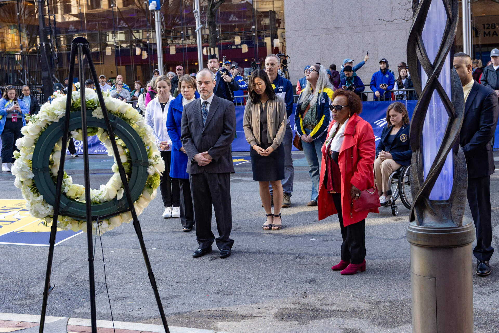 Gov. Healey, Mayor Wu and family of the victims pause for a moment of silence at the memorial on Boylston Street in Boston. (Jesse Costa/WBUR)