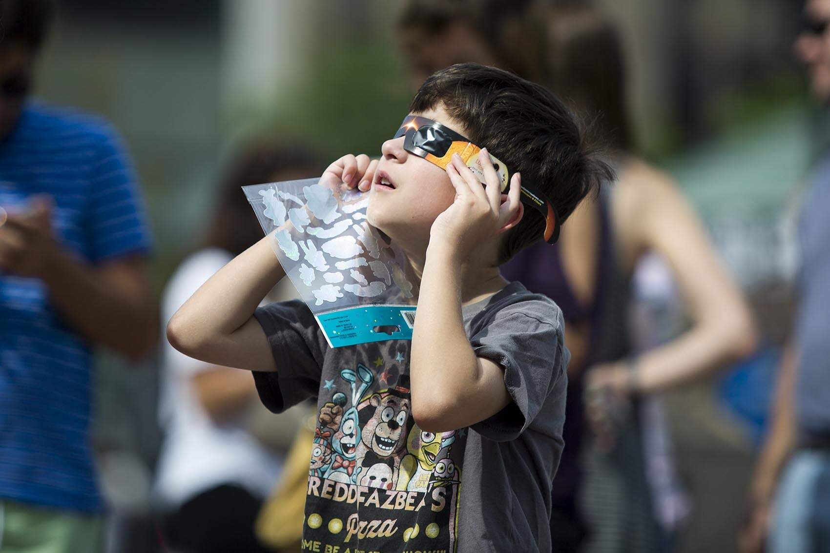 Christopher Griffith, 8, from Roslindale, Mass., looks up at the solar eclipse from Copley Square. (Robin Lubbock/WBUR)