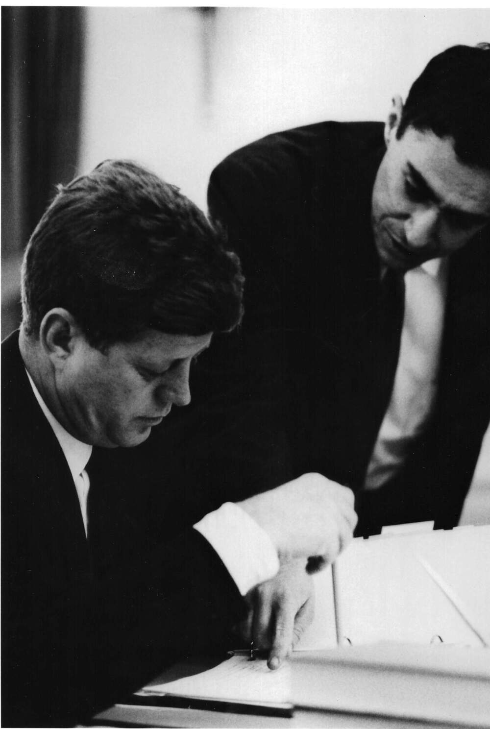 Dick Goodwin leans over the desk as President John F. Kennedy works with him on a speech draft. (Jacques Lowe/Courtesy of the Jacques Lowe Estate)