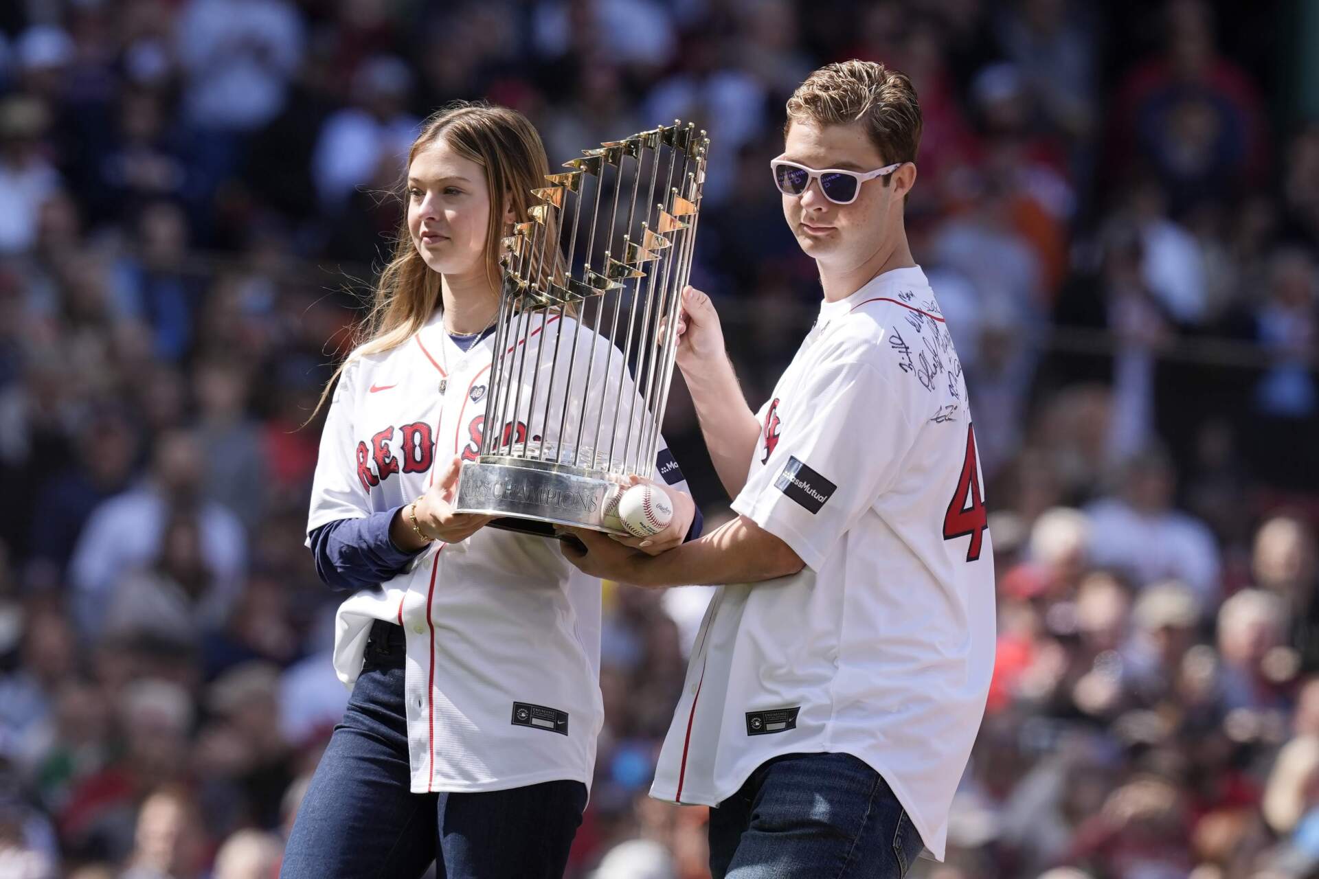 Children of former Boston Red Sox's Tim Wakefield, Brianna, left, and Trevor carry the World Series trophy after Brianna threw out the ceremonial first pitch during pre-game ceremonies before an opening-day baseball game at Fenway Park against the Baltimore Orioles, Tuesday, April 9, 2024, in Boston. (Michael Dwyer/AP)