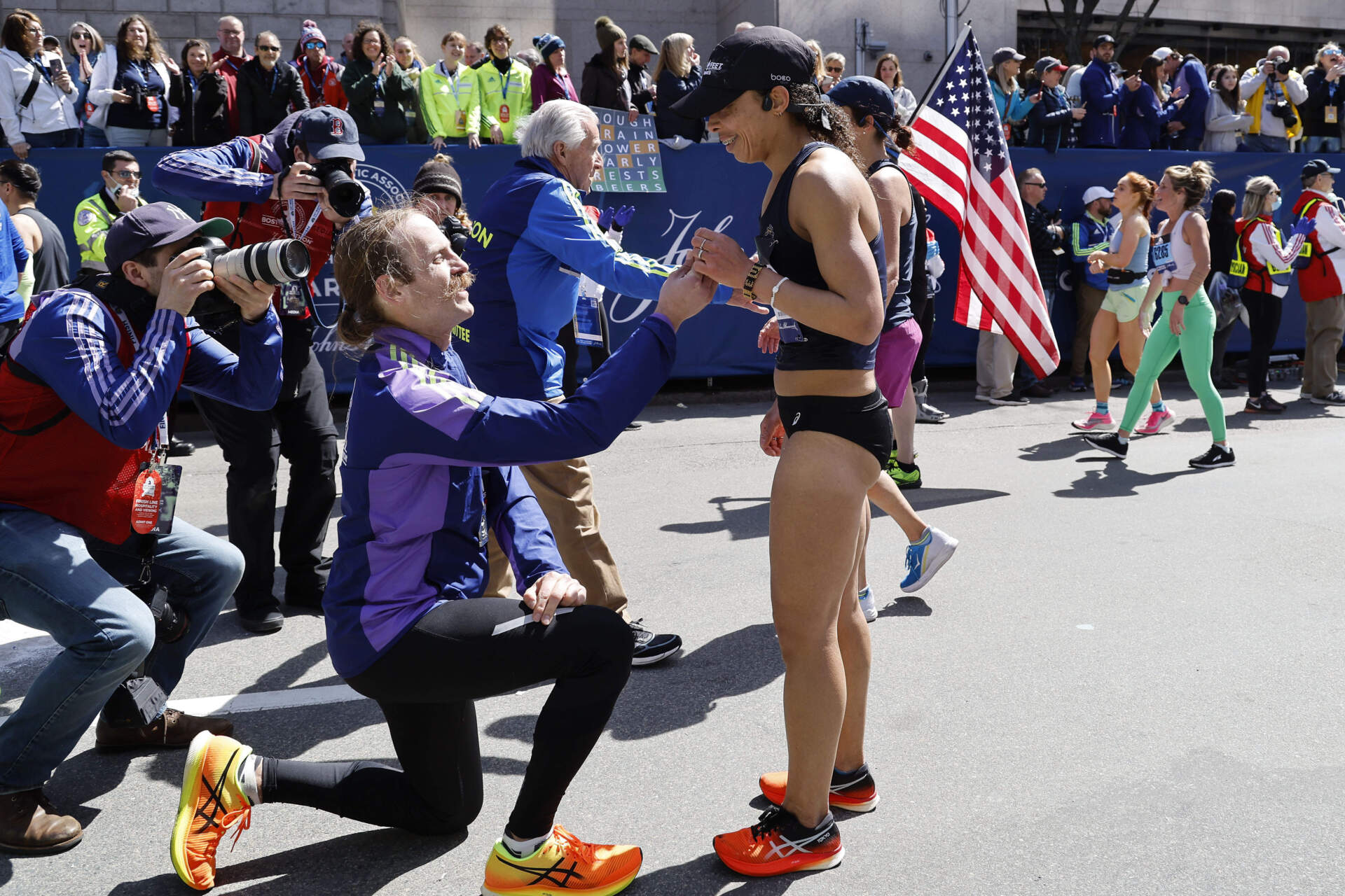 Alban Crook, of Iowa, gets down on one knee to propose to Karen Brophy, also of Iowa, at the finish line of the 126th Boston Marathon. (Winslow Townson/AP)
