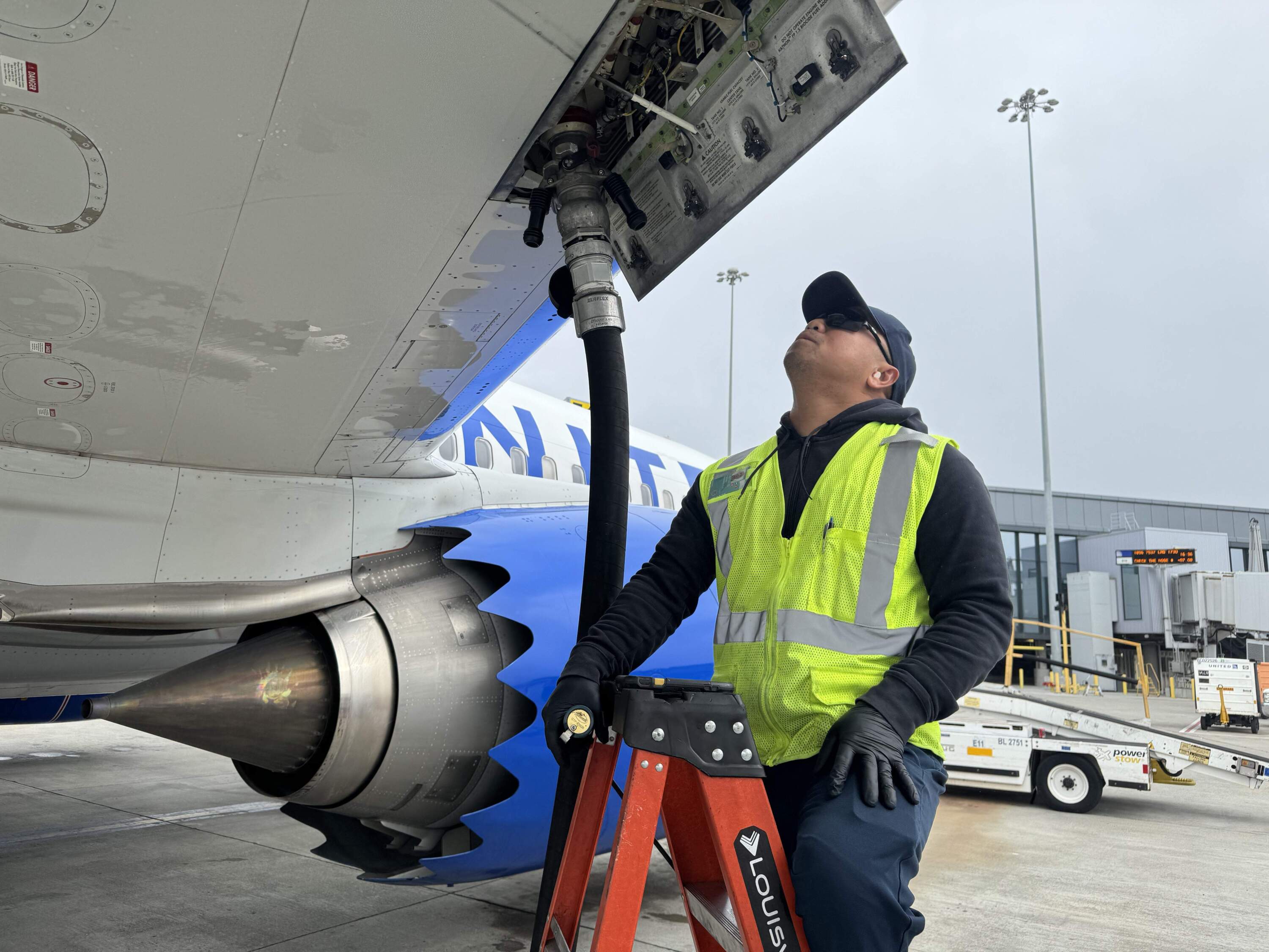 A worker at San Francisco International Airport refuels a 737 Max 9 plane with a blend of sustainable aviation fuel. (Chris Bentley/Here &amp; Now)