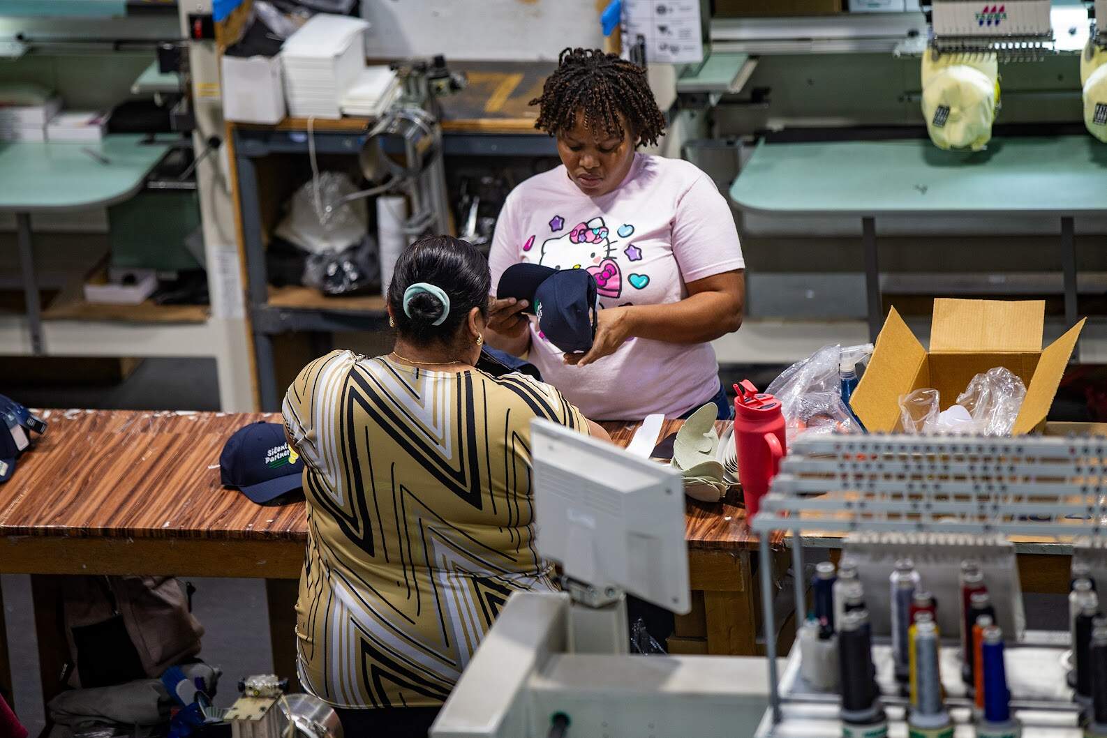 Musette Jean-Pierre inspects a hat before packing it up for shipping at Ahead in New Bedford. (Jesse Costa/WBUR)