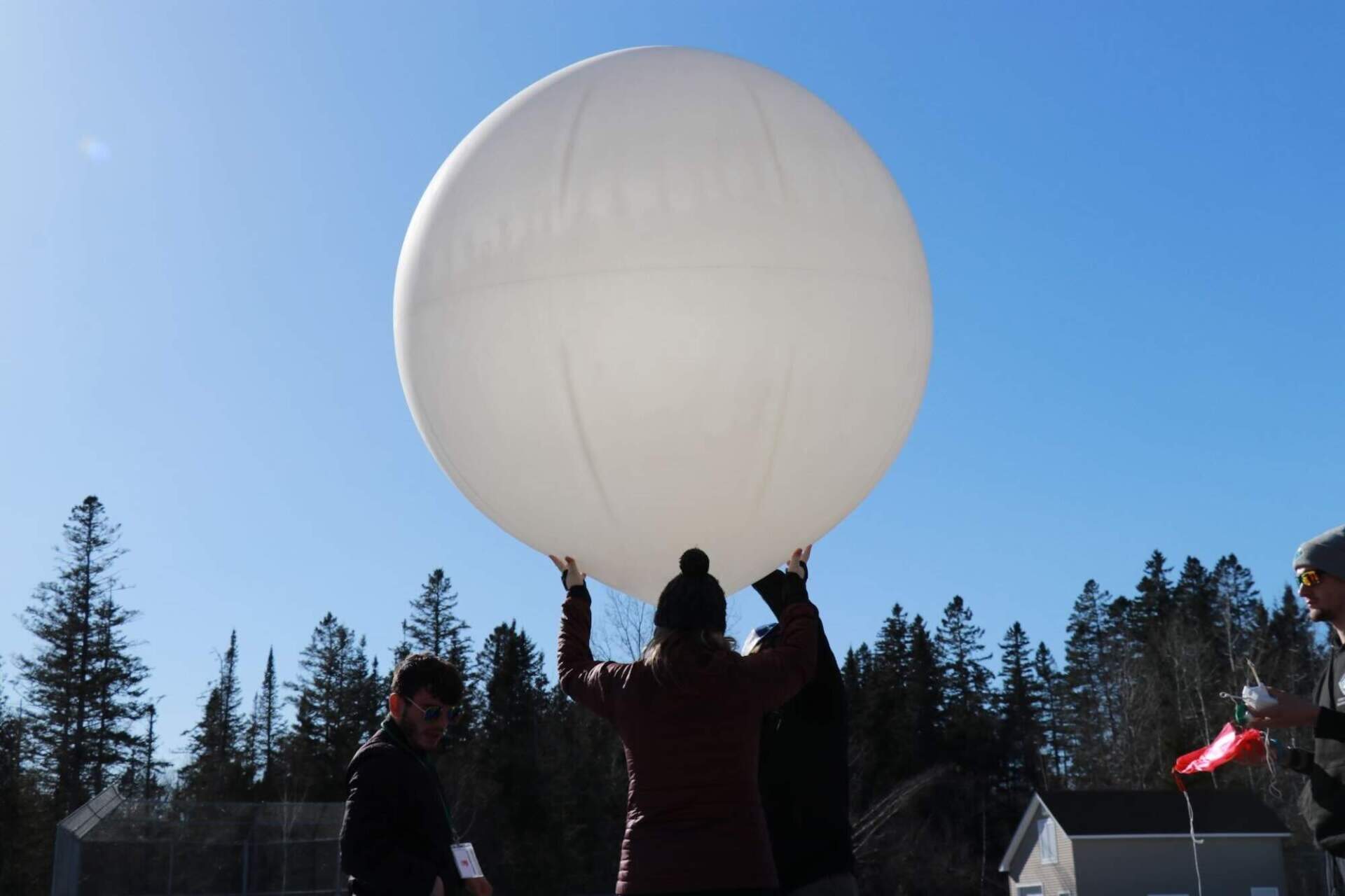 Plymouth State University students and professor on the NASA eclipse ballooning team prepare a weather balloon for launch in Pittsburg, New Hampshire. (Zoey Knox/NHPR)