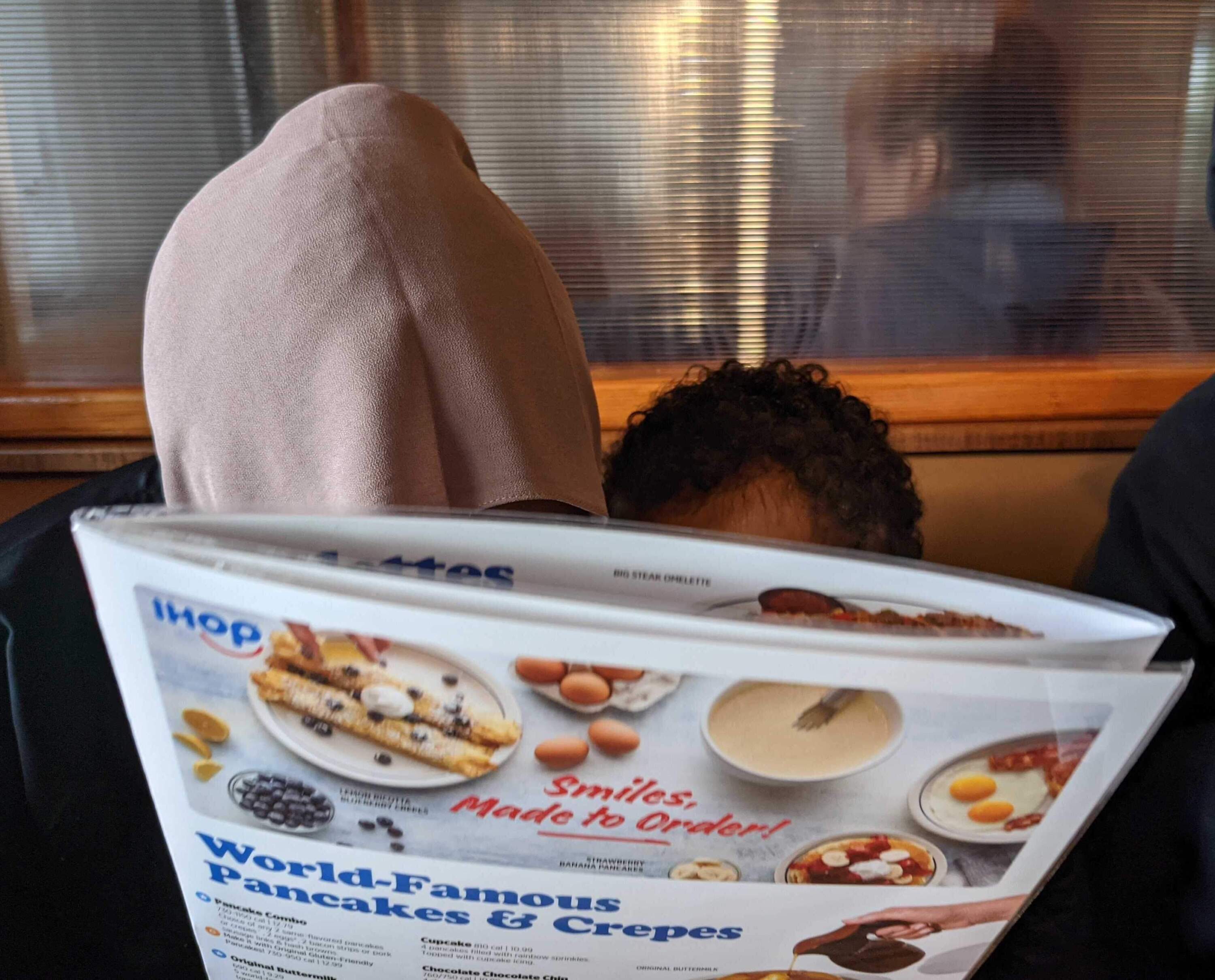 Associate producer Hanna Ali's two youngest siblings look over an IHOP menu together on Eid in 2022.
