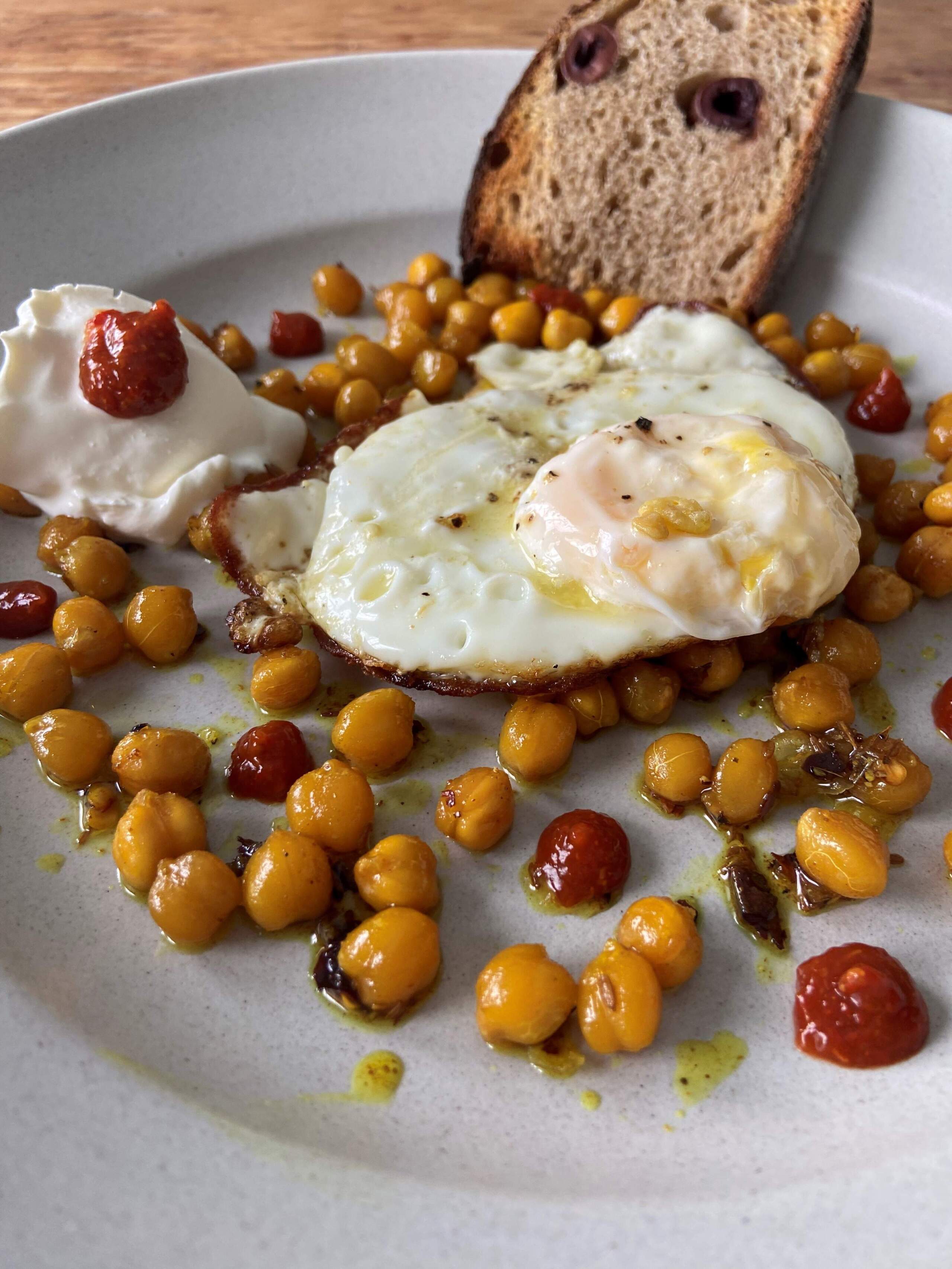 Olive oil-fried eggs with spiced roasted chickpeas, harissa and sour cream. (Kathy Gunst/Here & Now)
