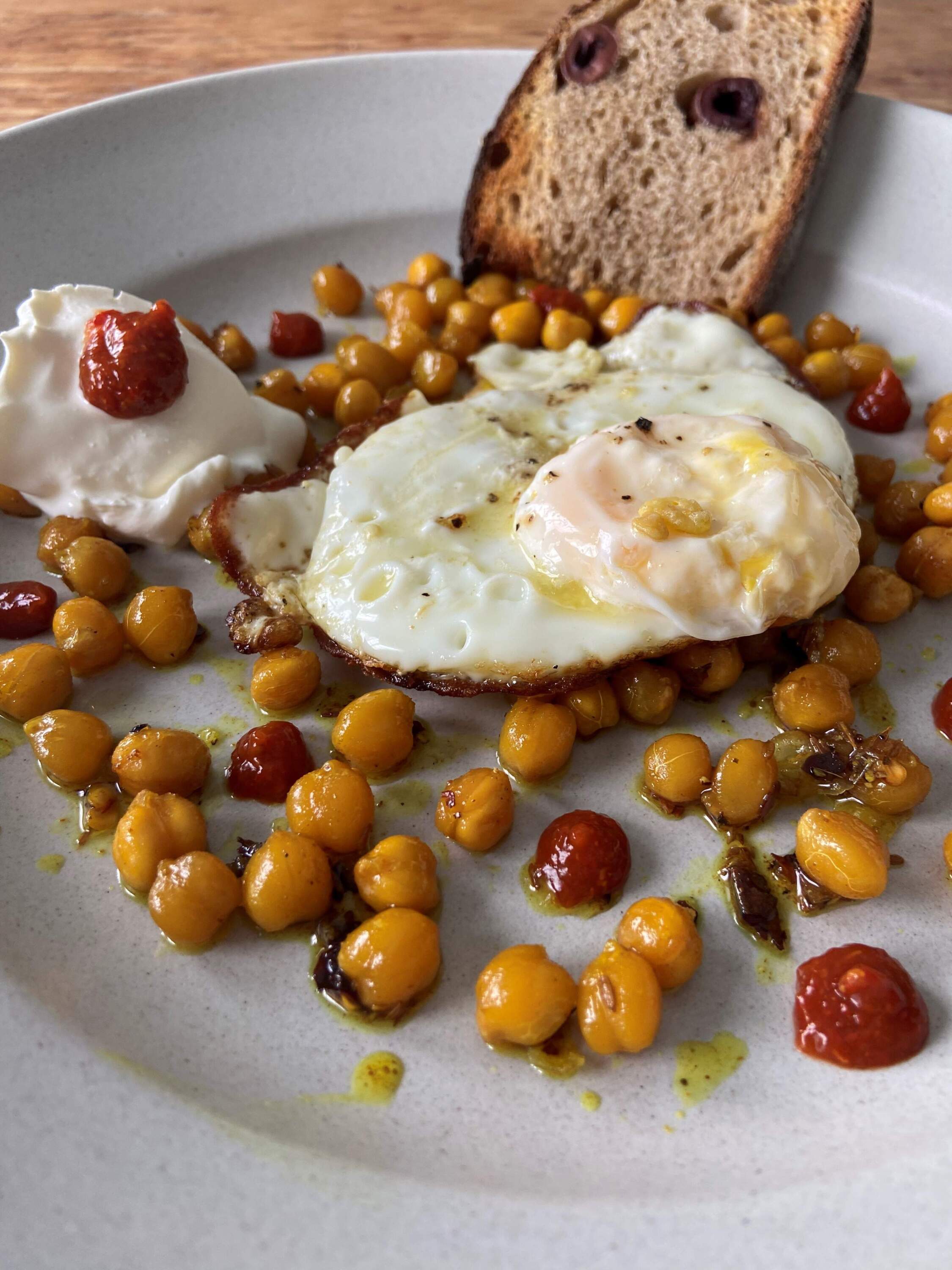 Olive oil-fried eggs with spiced roasted chickpeas, harissa and sour cream. (Kathy Gunst/Here &amp; Now)