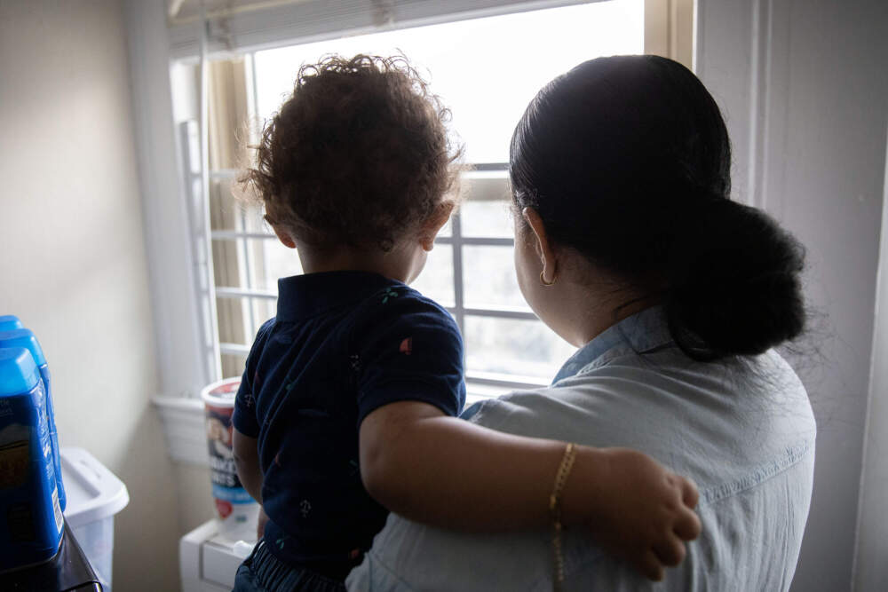 Ericka Guerrero and her toddler son Leudi look out the window of their shelter room in Brookline. (Robin Lubbock/WBUR)